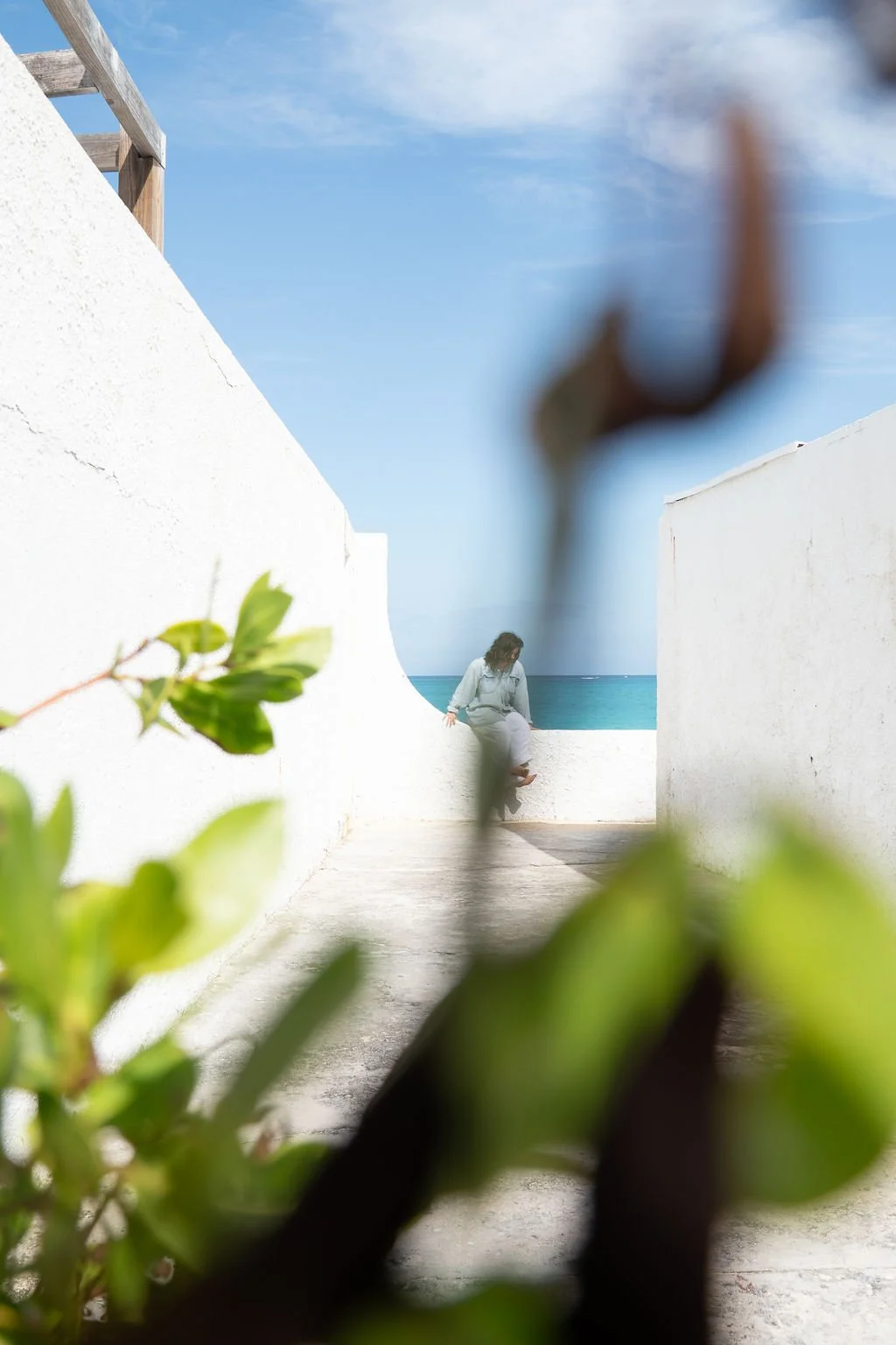 A woman meditates on a wall overlooking the sea.