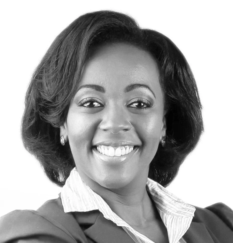 Black and white photo of a smiling woman with shoulder-length hair, wearing a collared shirt and earrings.