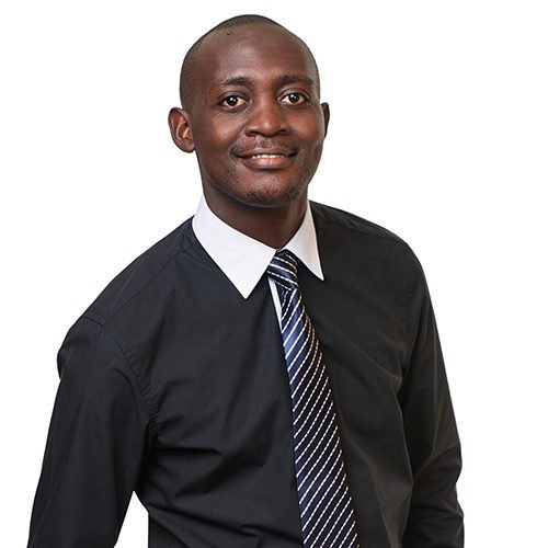 A man in a black dress shirt and striped tie smiling against a white background.
