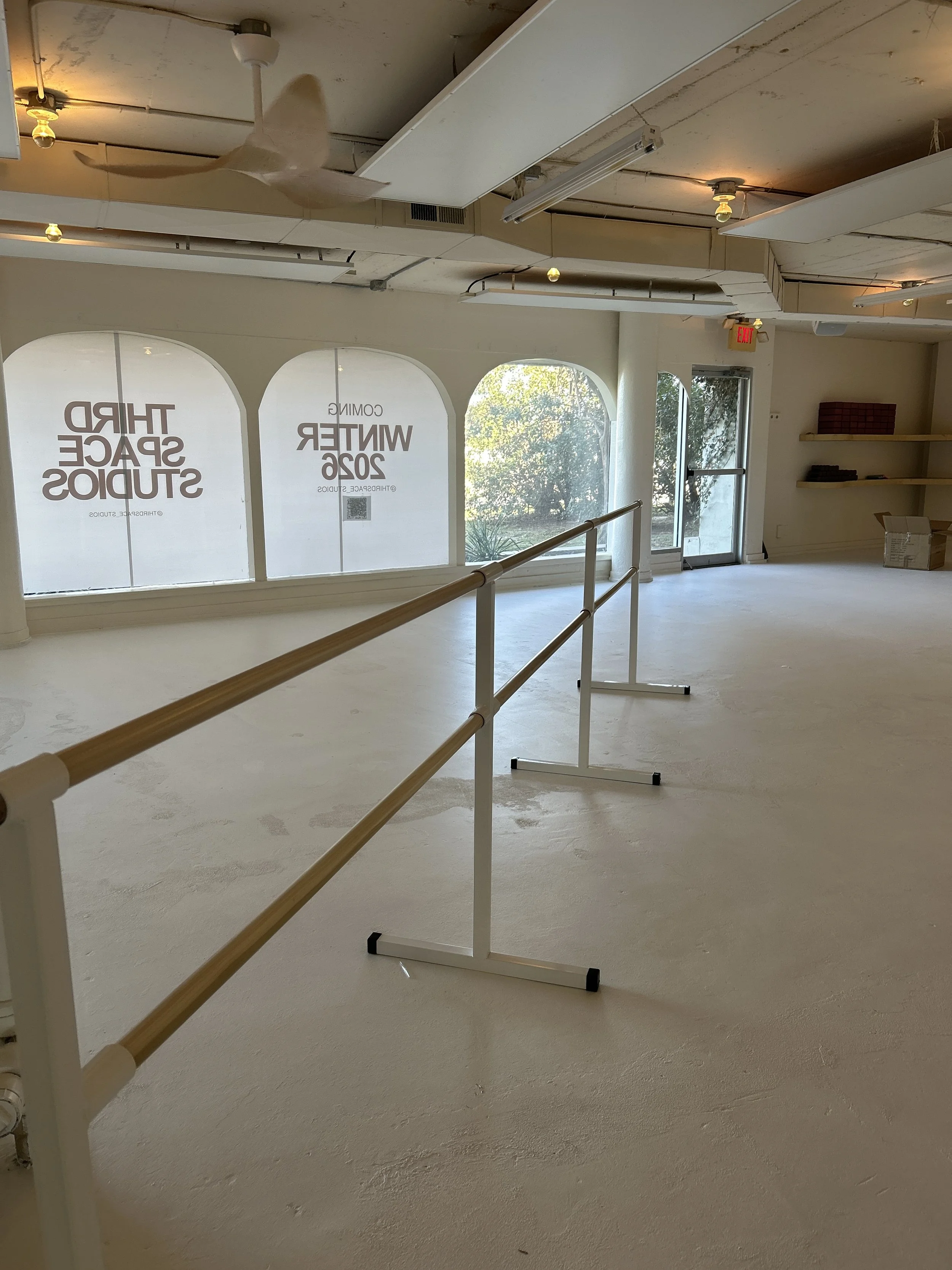 Bright heated mat studio at Third Space Studios with barre rails, arched windows, and open floor space