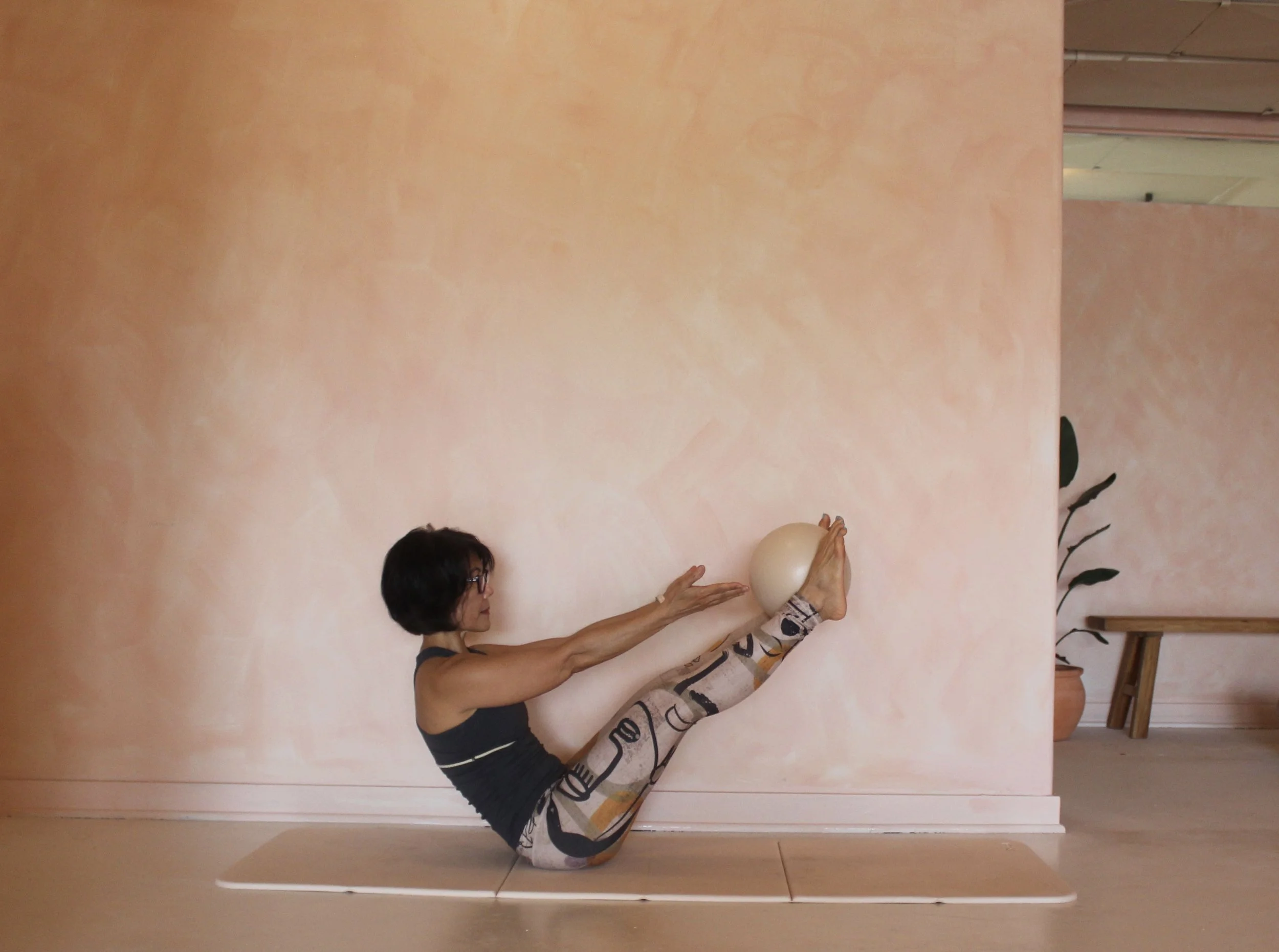 Pilates instructor Toanne performing a seated balance pose on a studio floor at Third Space Studios in Houston