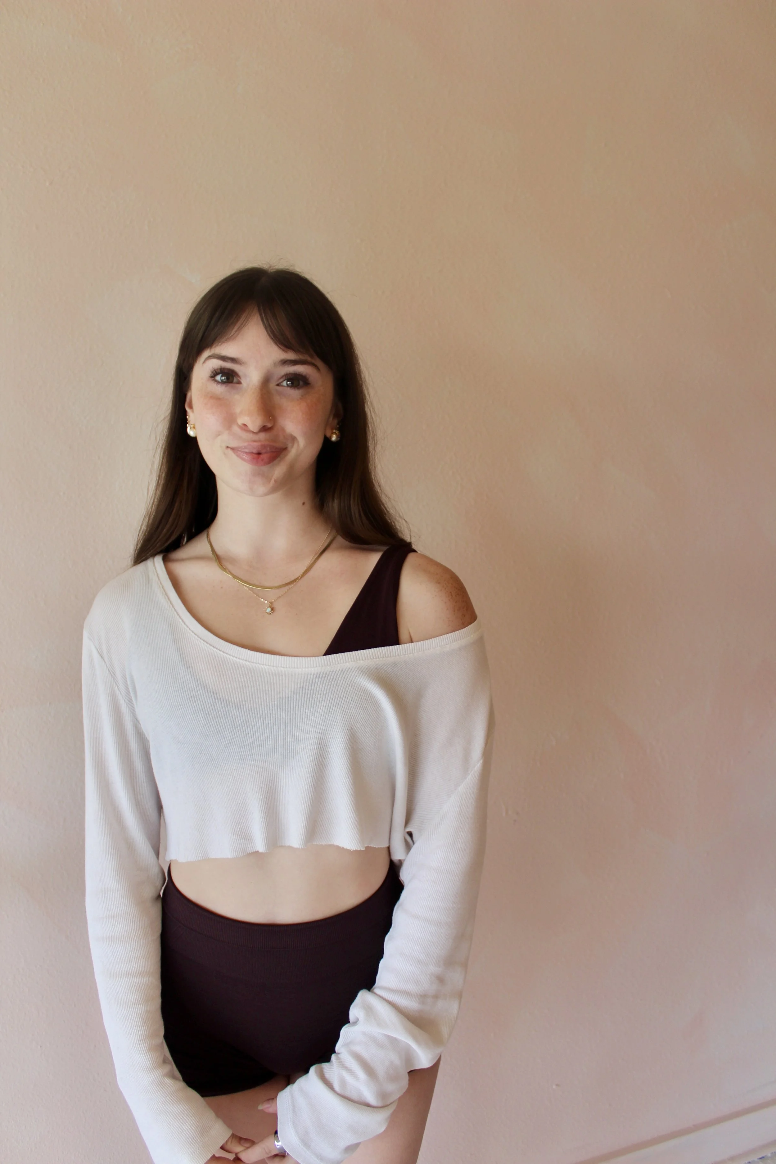 Fionna, pilates instructor at Third Space Studios in Houston, TX, posing in a white off-shoulder top and dark leggings