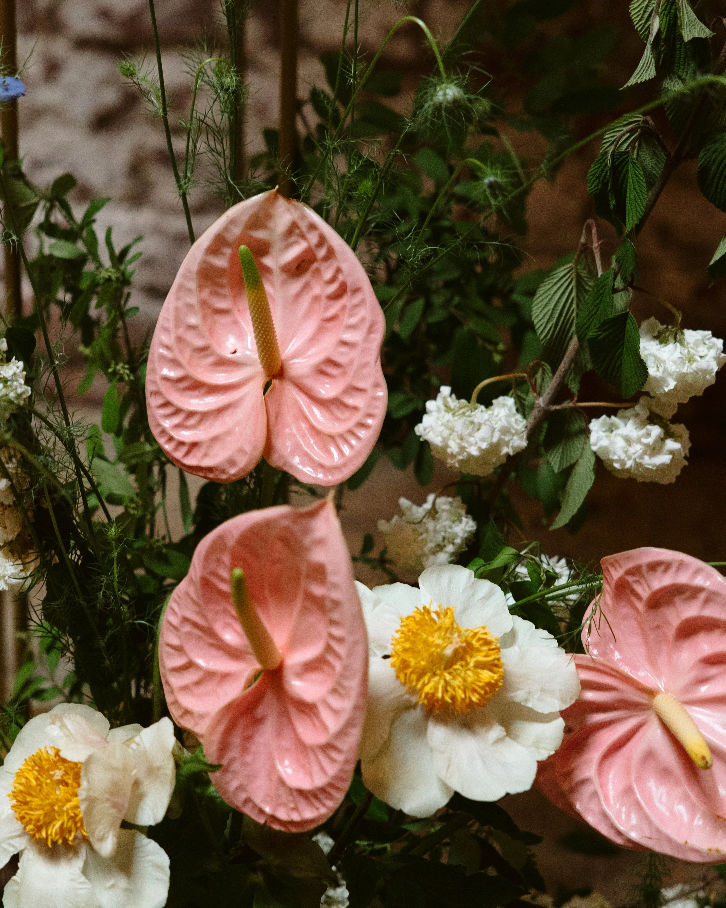 A bouquet of flowers with pink anthuriums, white blossoms, and green foliage. marigolds florals nyc florist wedding florals houston hall nyc bar wedding