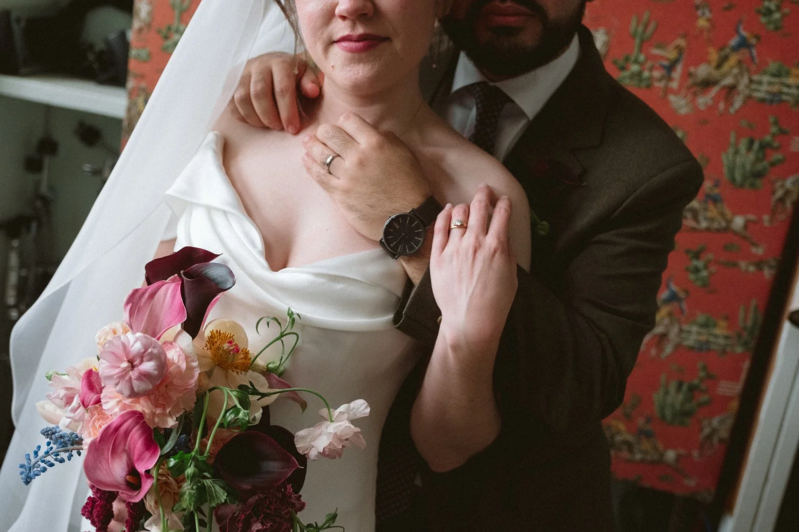 A bride and groom taking a close-up mirror selfie, with the bride holding a large bouquet of pink, purple, and red flowers, and both wearing wedding rings. marigolds florals nyc florist wedding florals atmosfera wedding
