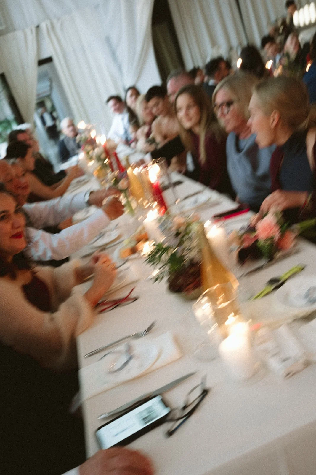 People seated at a long dining table during a festive celebration or dinner party, with candles, flowers, and decorations. marigolds florals nyc florist wedding florals atmosfera wedding intimate wedding
