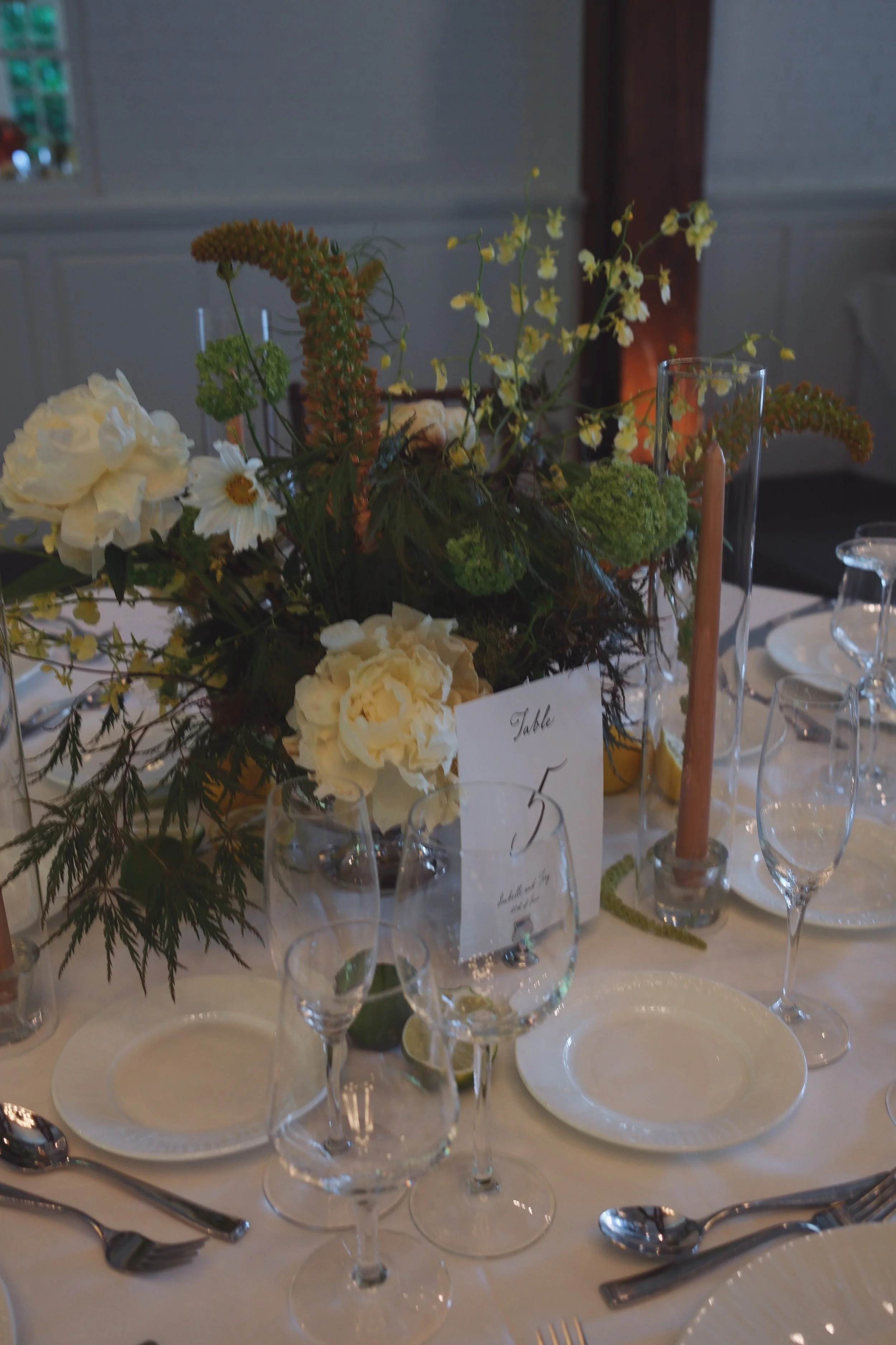 Elegant table setting with a floral centerpiece, wine glasses, plates, silverware, and candles for a formal event. marigolds florals nyc florist wedding florals central park boathouse wedding