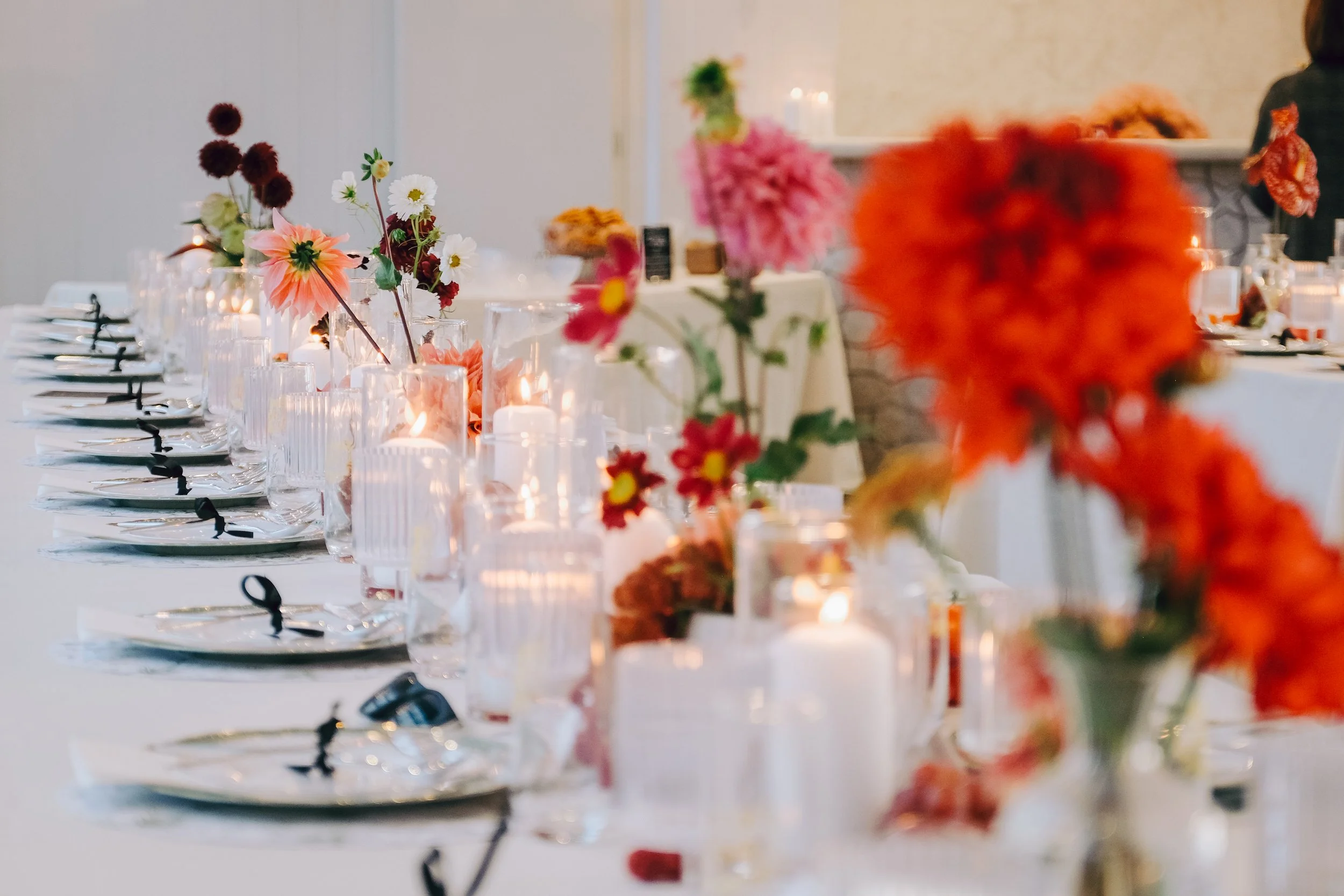 A decorated dining table with floral centerpieces and candles for a celebration or event. marigolds florals nyc florist wedding florals the w loft wedding pedestal wedding ceremony anthurium 