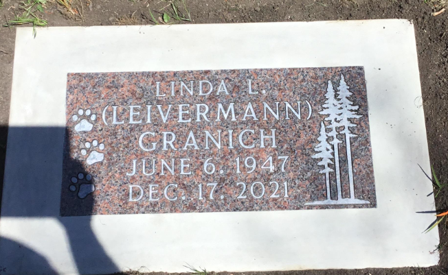 Gravestone with the name Linda L. Leivermann Granich, born June 6, 1947, died December 17, 2021, with paw print symbols and a tree design.