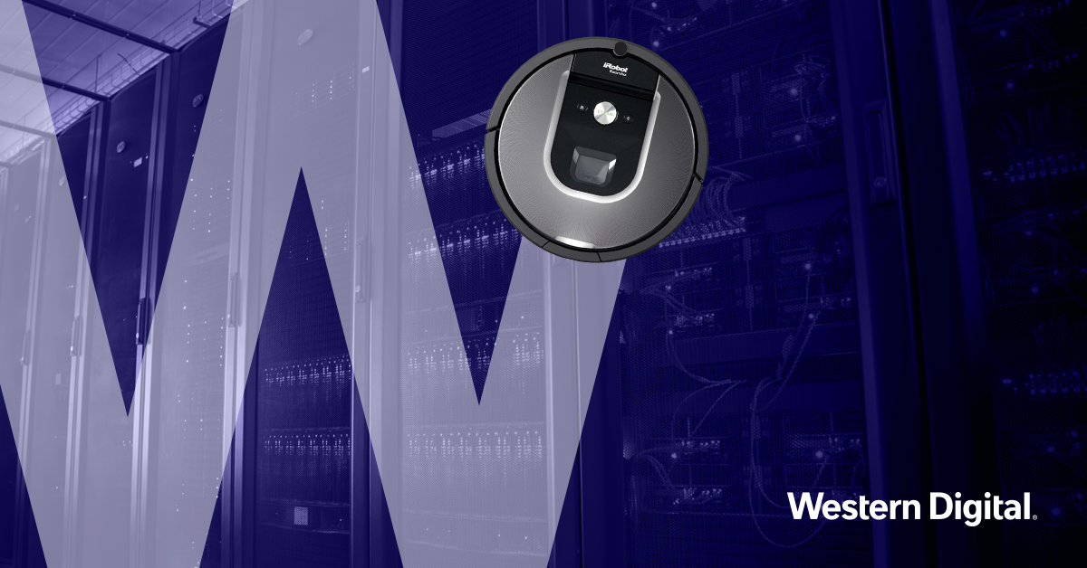 An iRobot Roomba vacuum cleaner in a data center with server racks, illuminated with blue lighting.