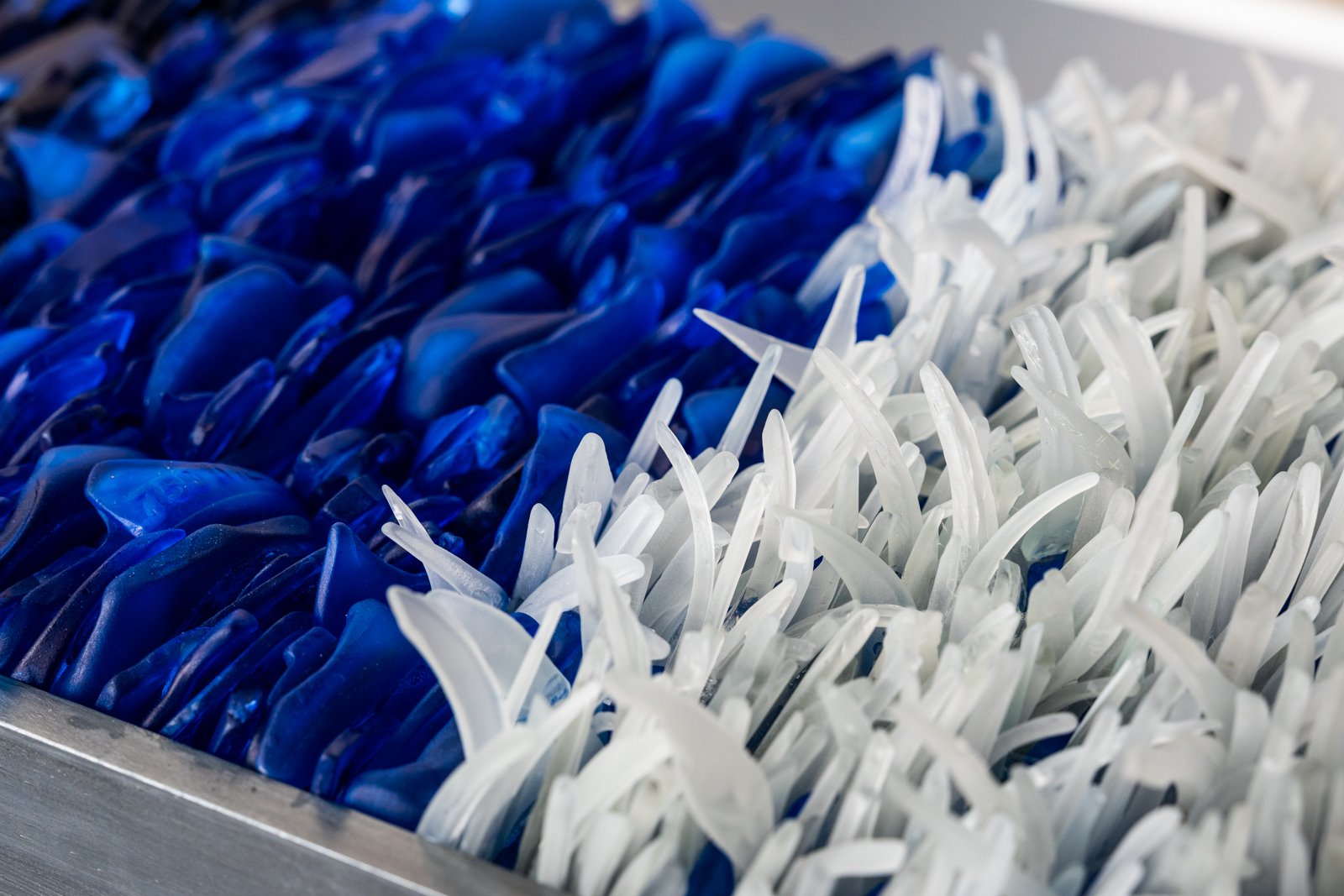 Upcycled hand dyed spirit bottles that looks like the ocean depths and a wave crashing 