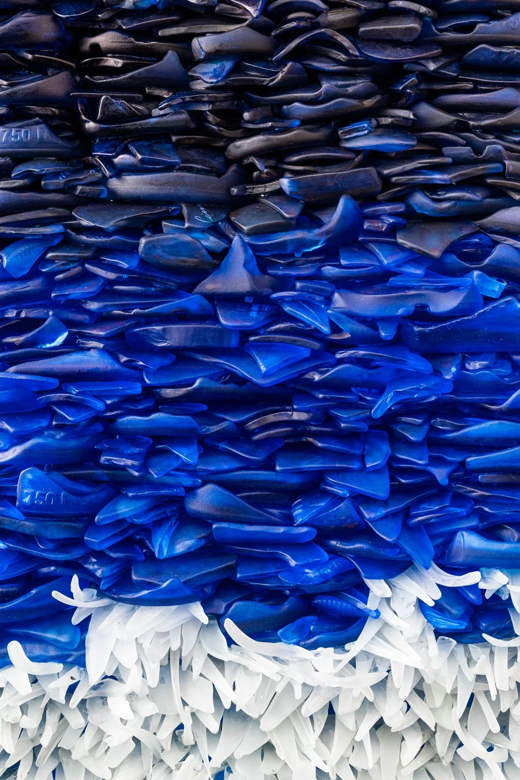 Upcycled hand dyed spirit bottles that looks like the ocean depths and a wave crashing 