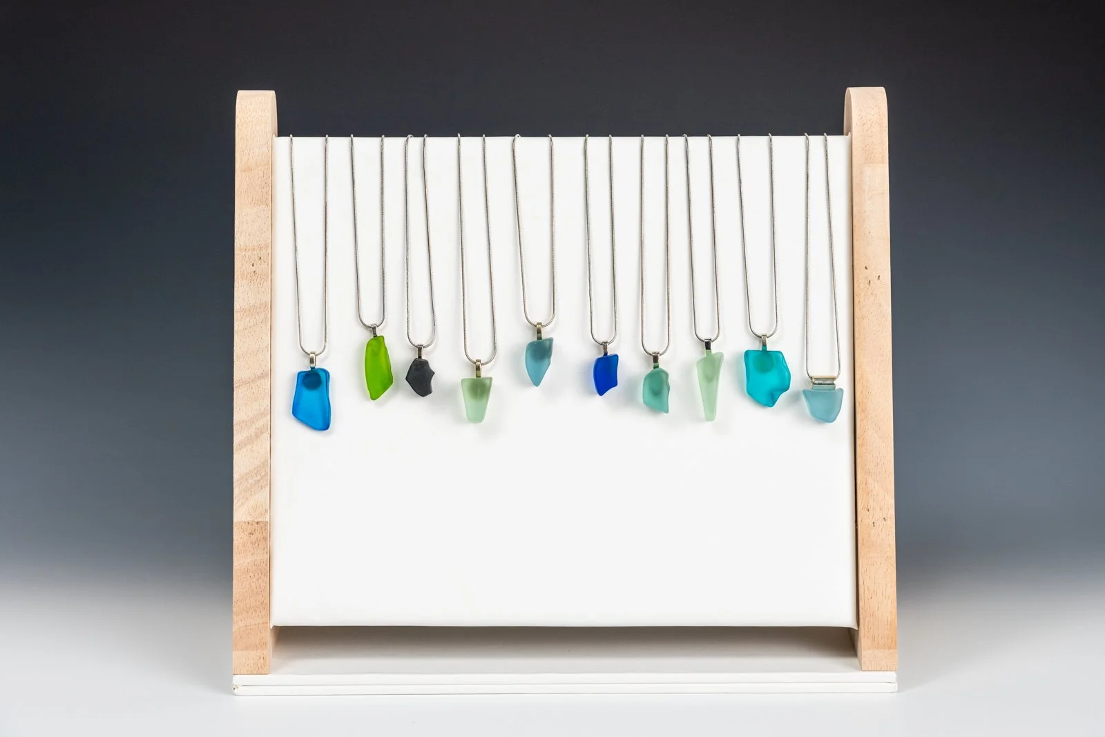 Handmade necklaces featuring unique fragments of reclaimed bottle glass, each piece naturally shaped and polished while retaining its organic edges. The glass varies in color and size, making every necklace a singular, wearable remnant of a larger wo