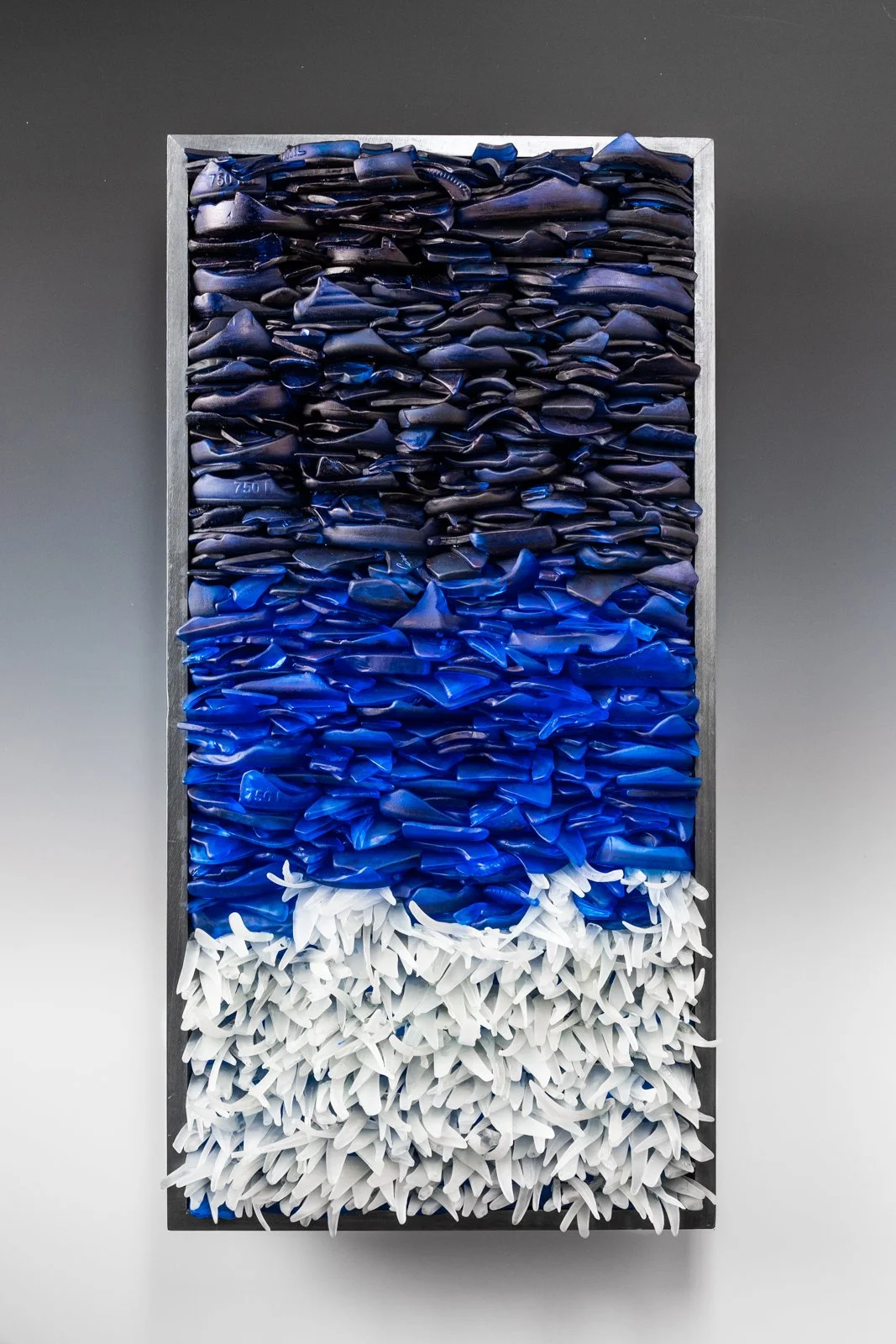 Upcycled hand dyed spirit bottles that looks like the ocean depths and a wave crashing 