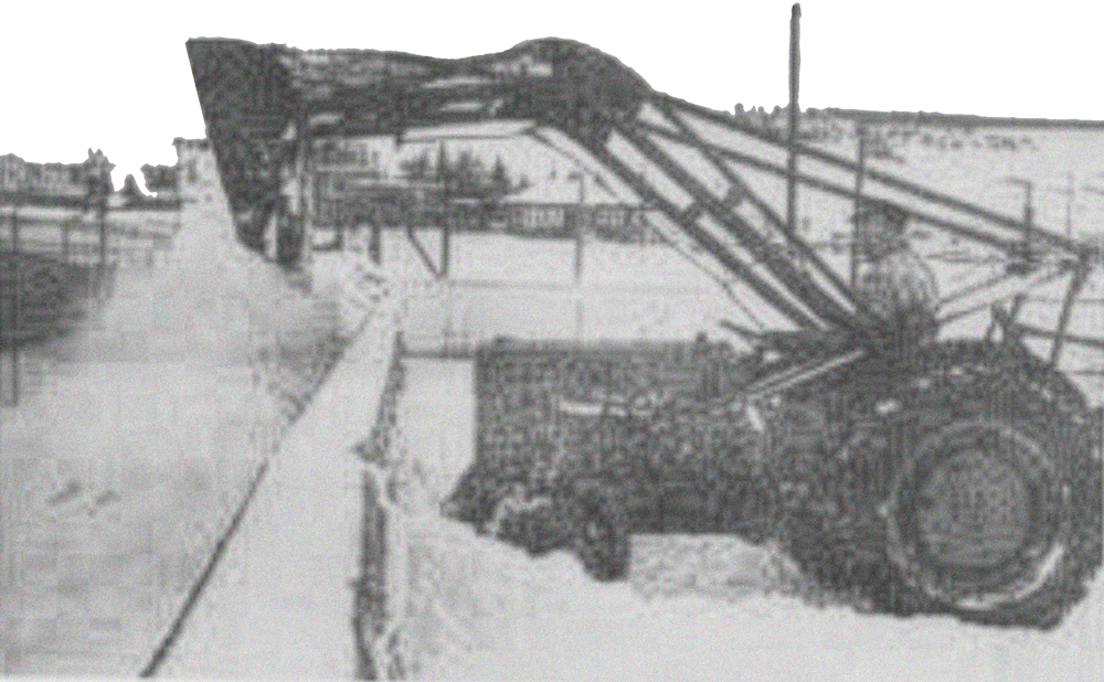 Black and white photo of large construction equipment, including a crane, on a construction site with snow.