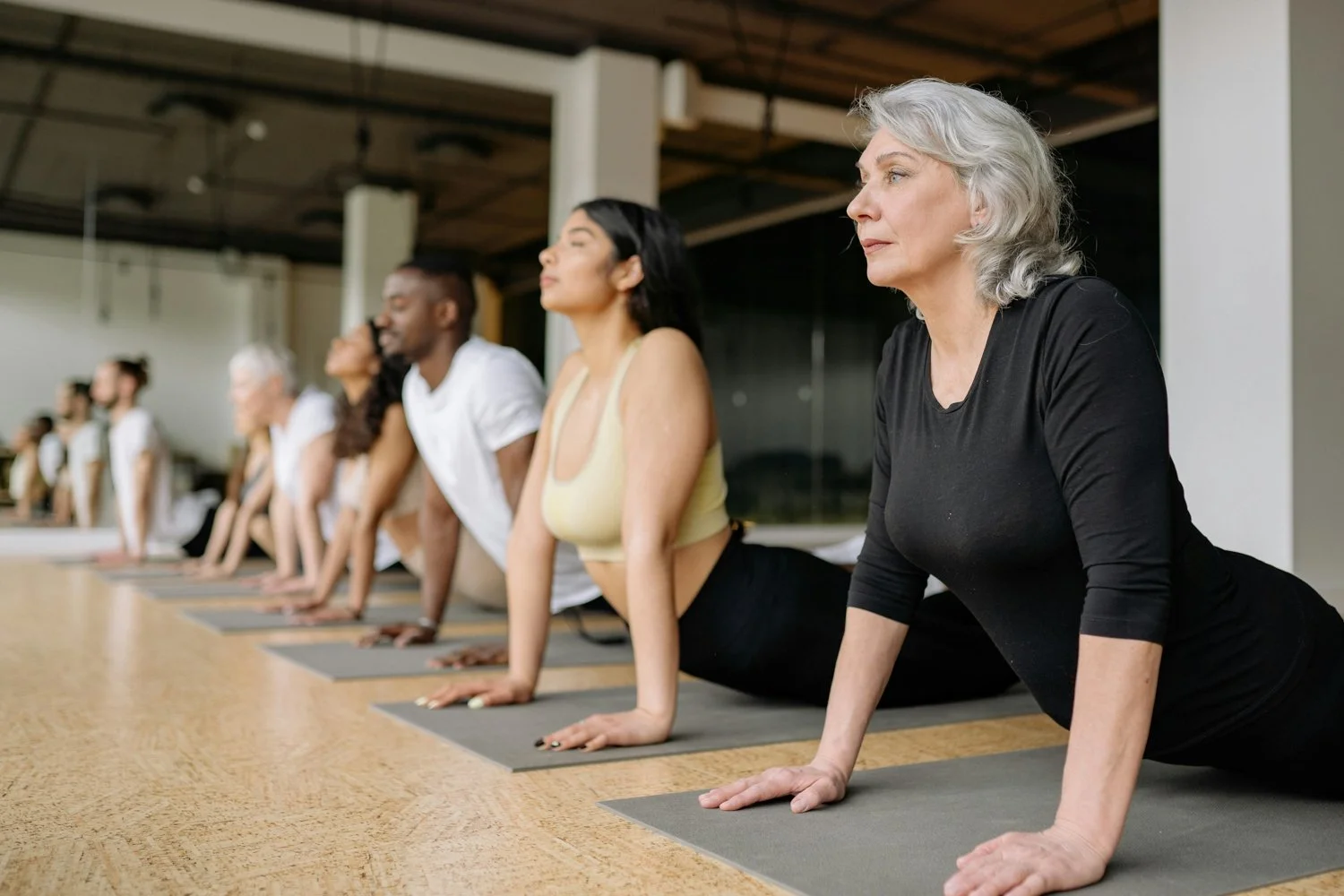 Group of people practicing yoga in a studio, doing Cobra pose