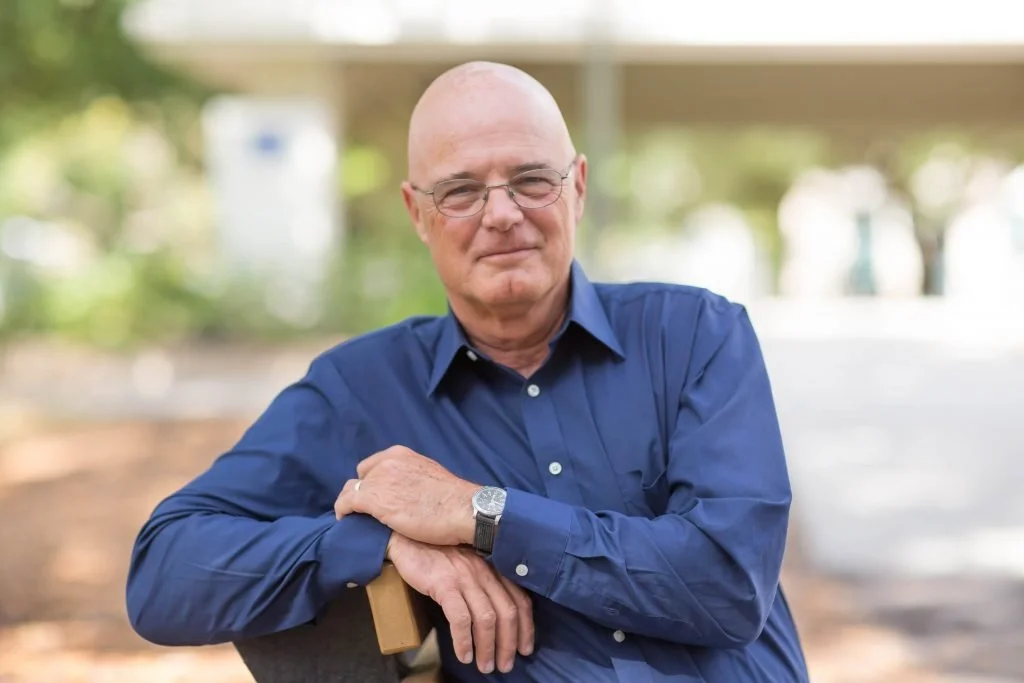 Headshot of Brian McLaren sitting on a bench outside. Brian is wearing a dark blue collared button up shirt.
