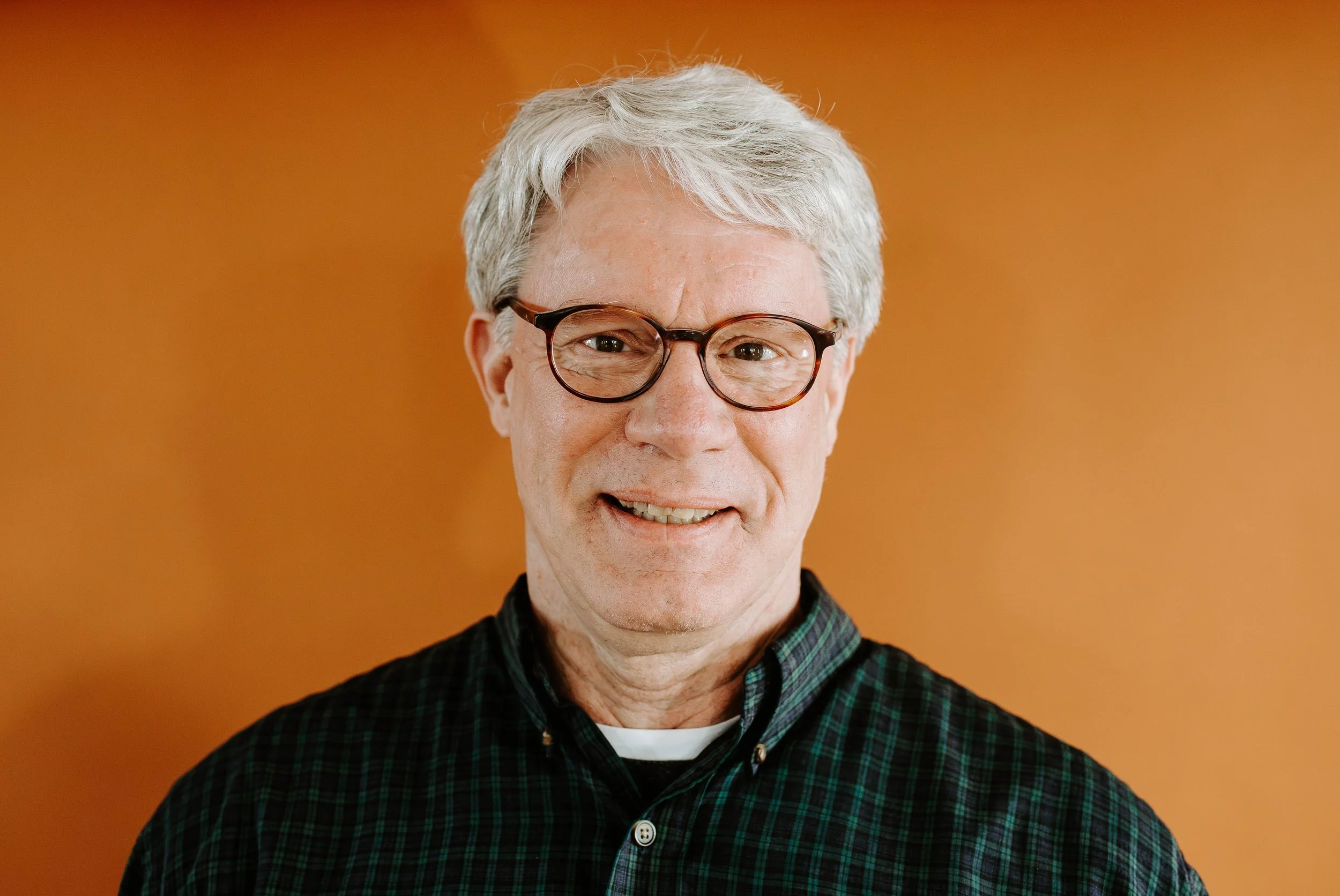 Headshot of Pete Enns smiling in front of an orange background.
