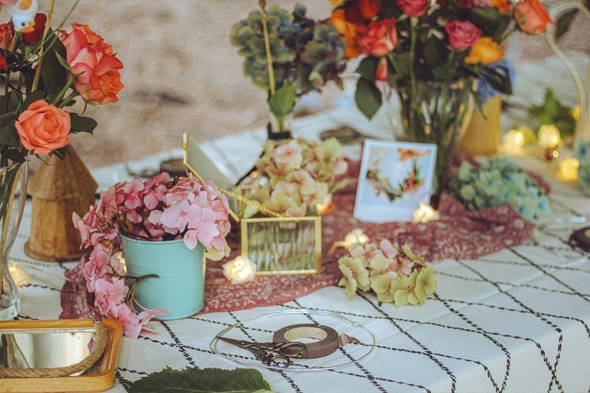 Floral arrangement on a decorated table with pink and peach flowers, a small note card, and string lights.