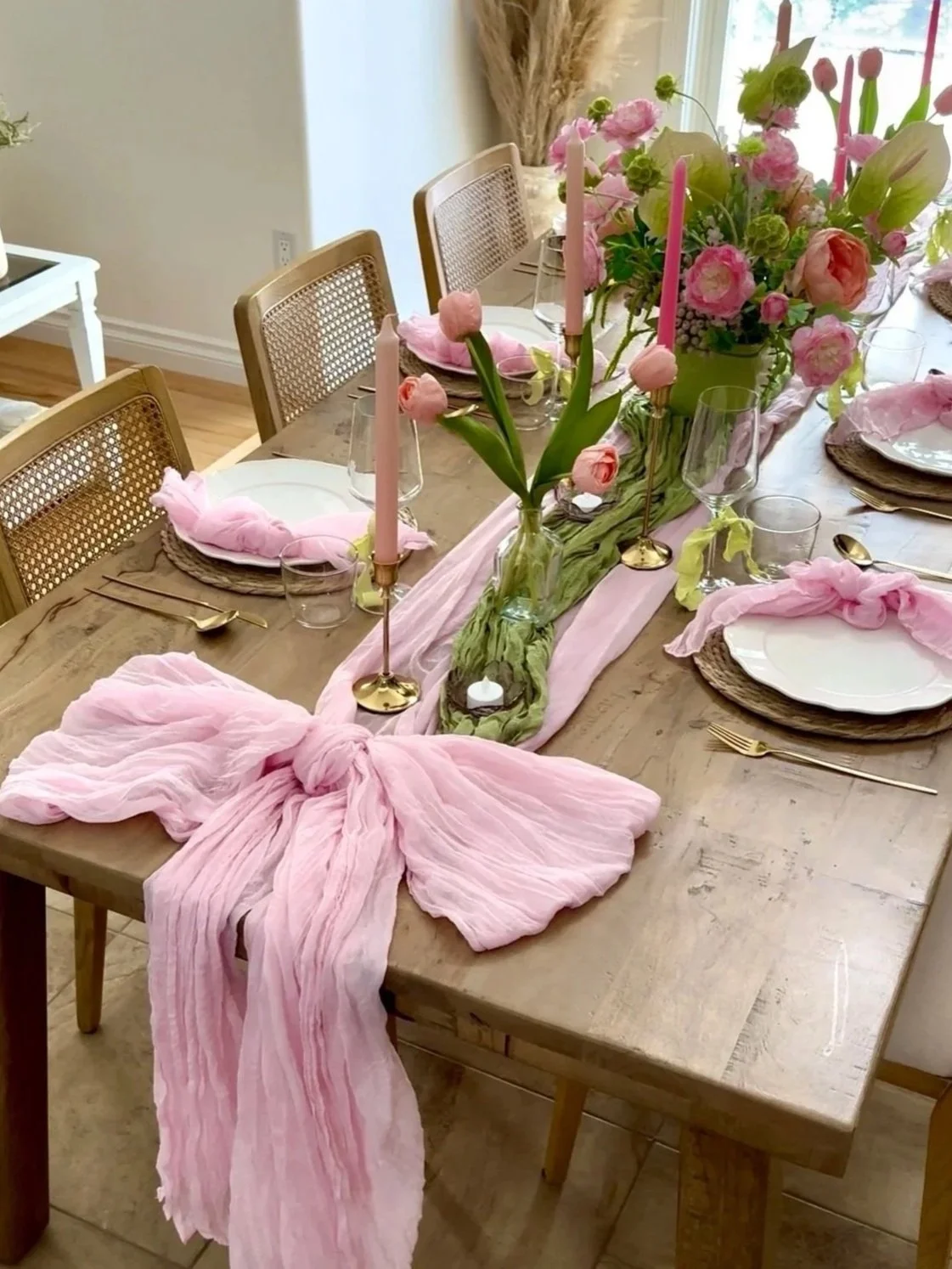 A Matcha in Bloom inspired dining tablescape rental perfect for a bridal shower, girls brunch, or spring set up. Includes pink and green florals, decoration, pink table linens with a bow, and white plates with gold cutlery.