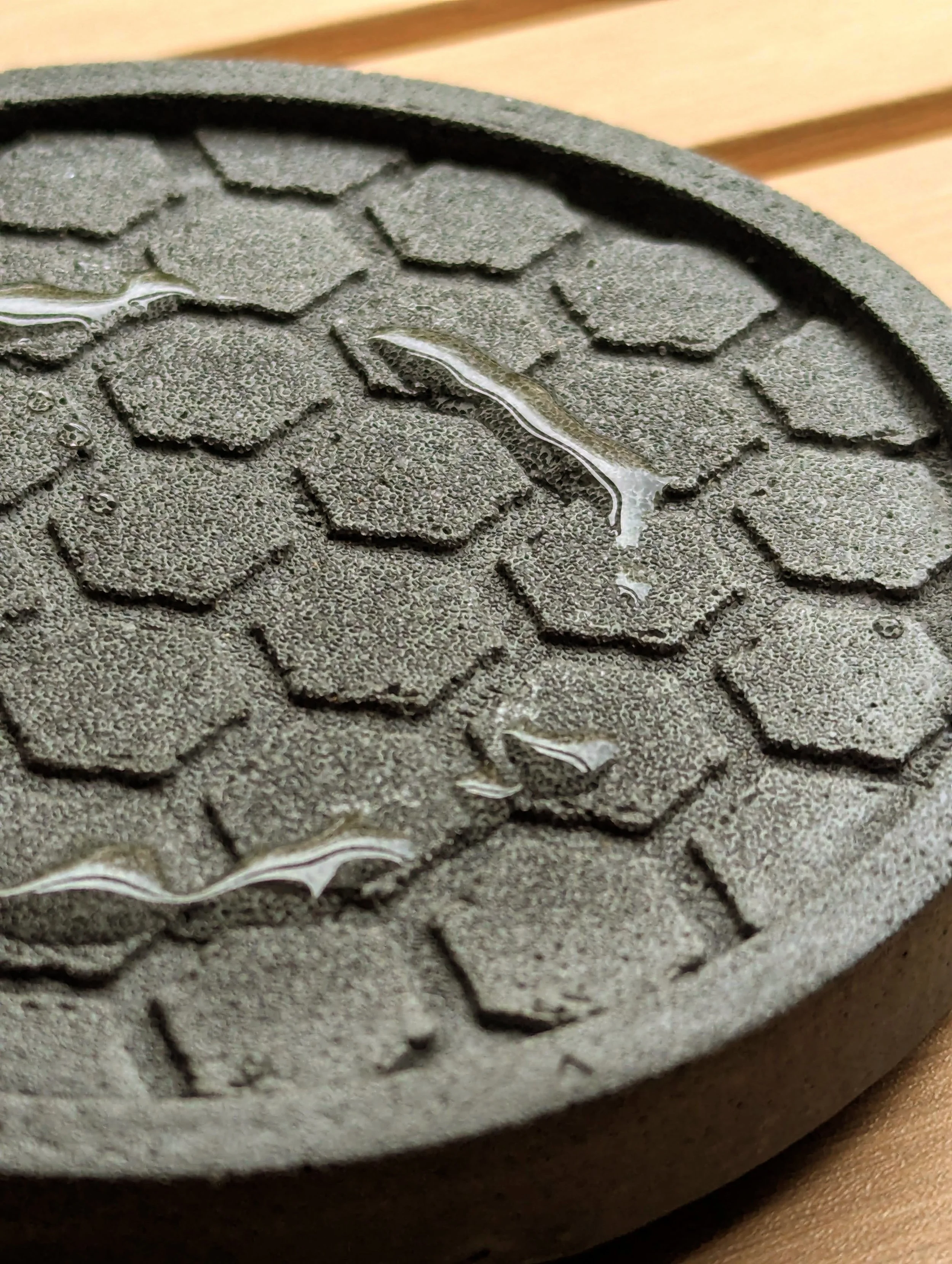 A close-up of a textured, hexagonal-patterned surface with small water droplets on it.