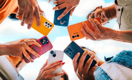 People holding smartphones in a circle checking their devices outdoors.