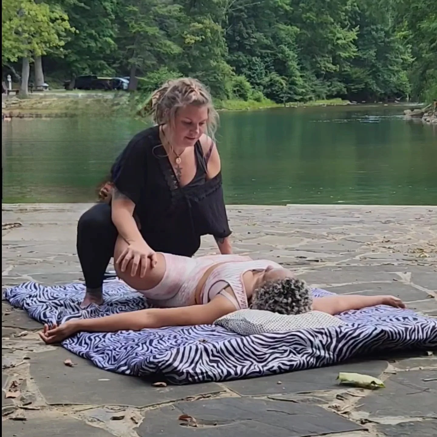 Thai Massage by the river at  at Blue Bend National Forrest. Surrounded by nature. Woman receiving is laying comfortably on a Thai Mat with a zebra print sheet and pillow under her