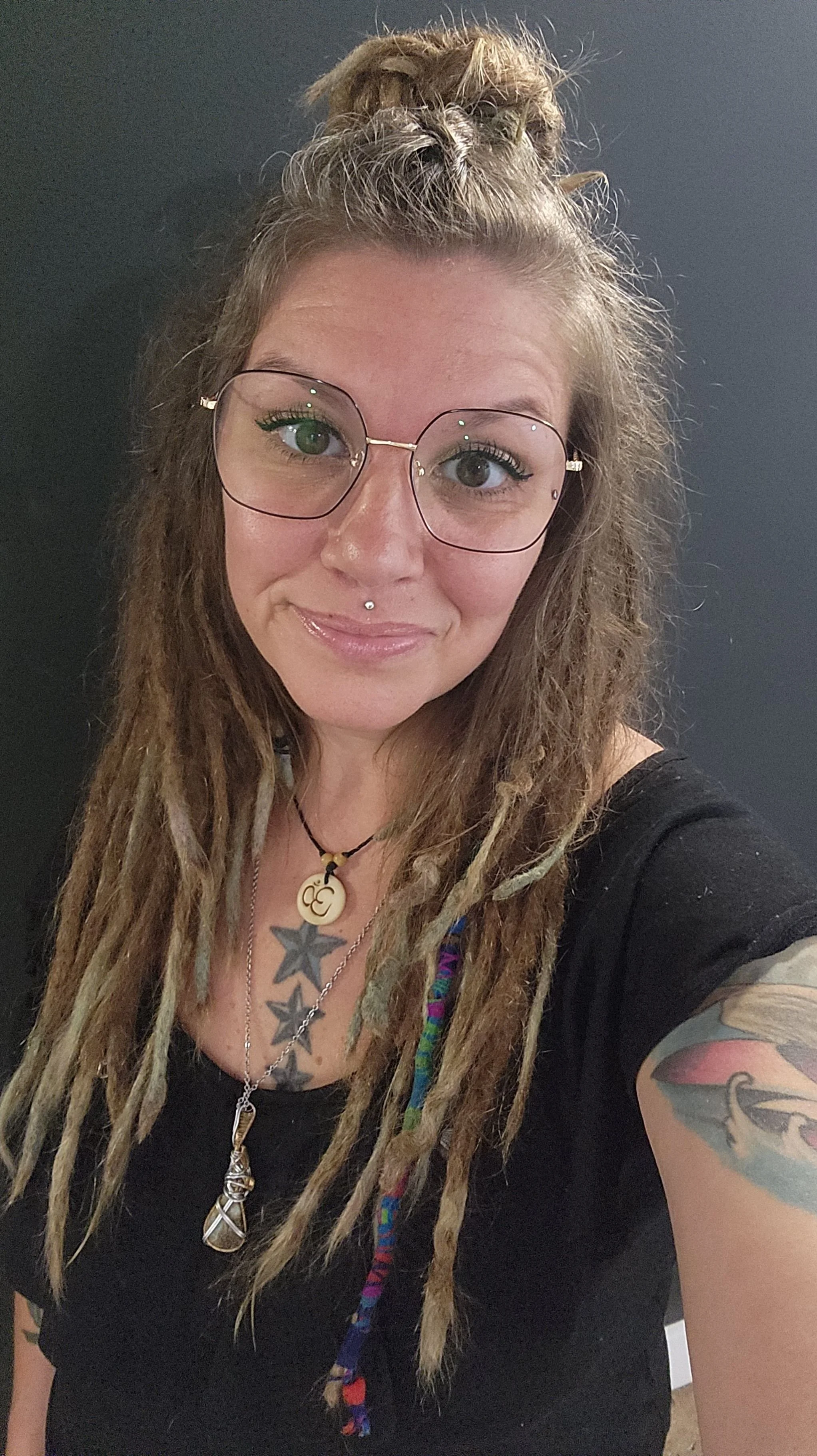 Jade Yates, Licensed Massage Therapist & Reiki Master Teacher. She has long dreadlocks, tattoos, piercings, glasses and a necklace.