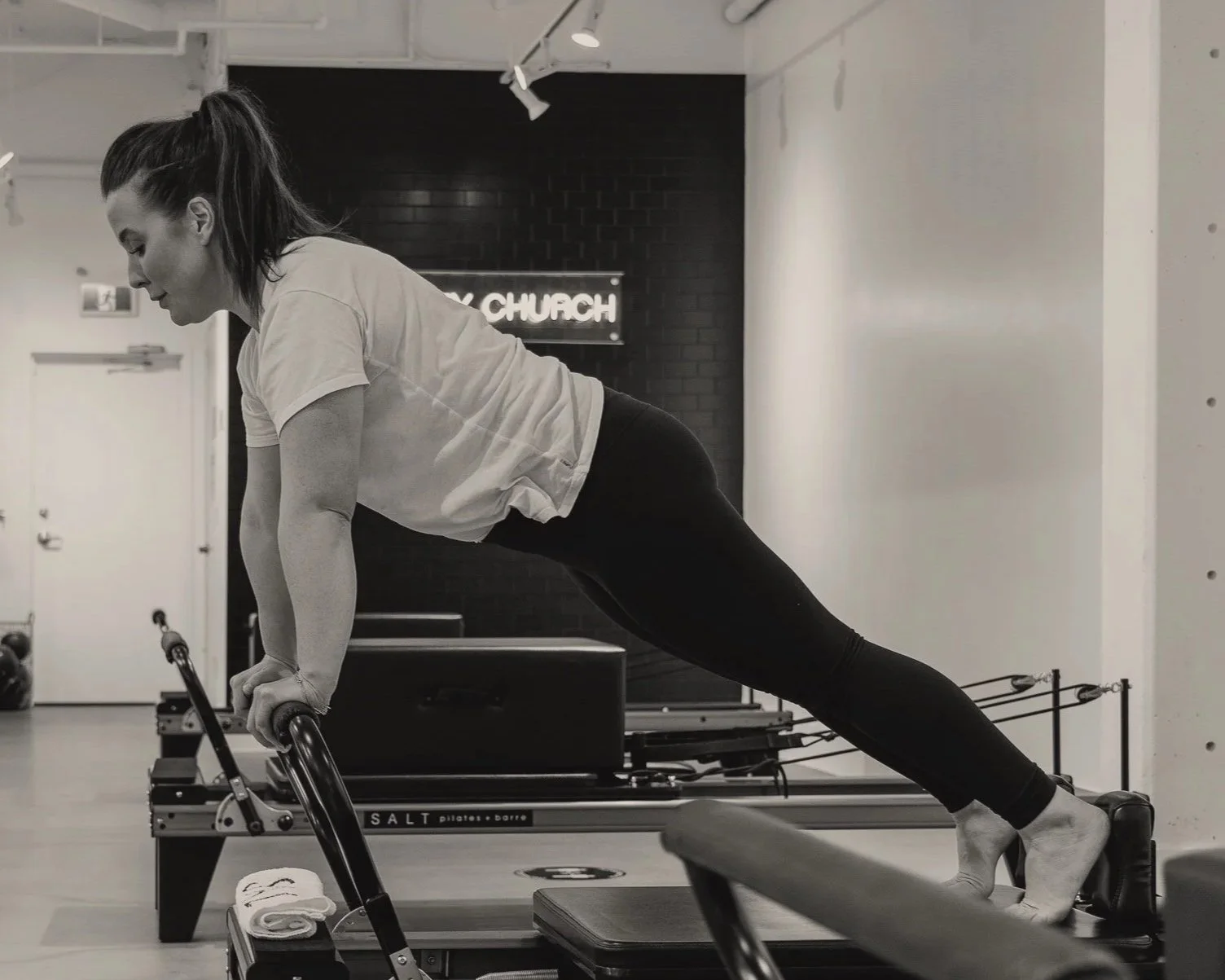black and white photo of a woman on a pilates reformer in a studio