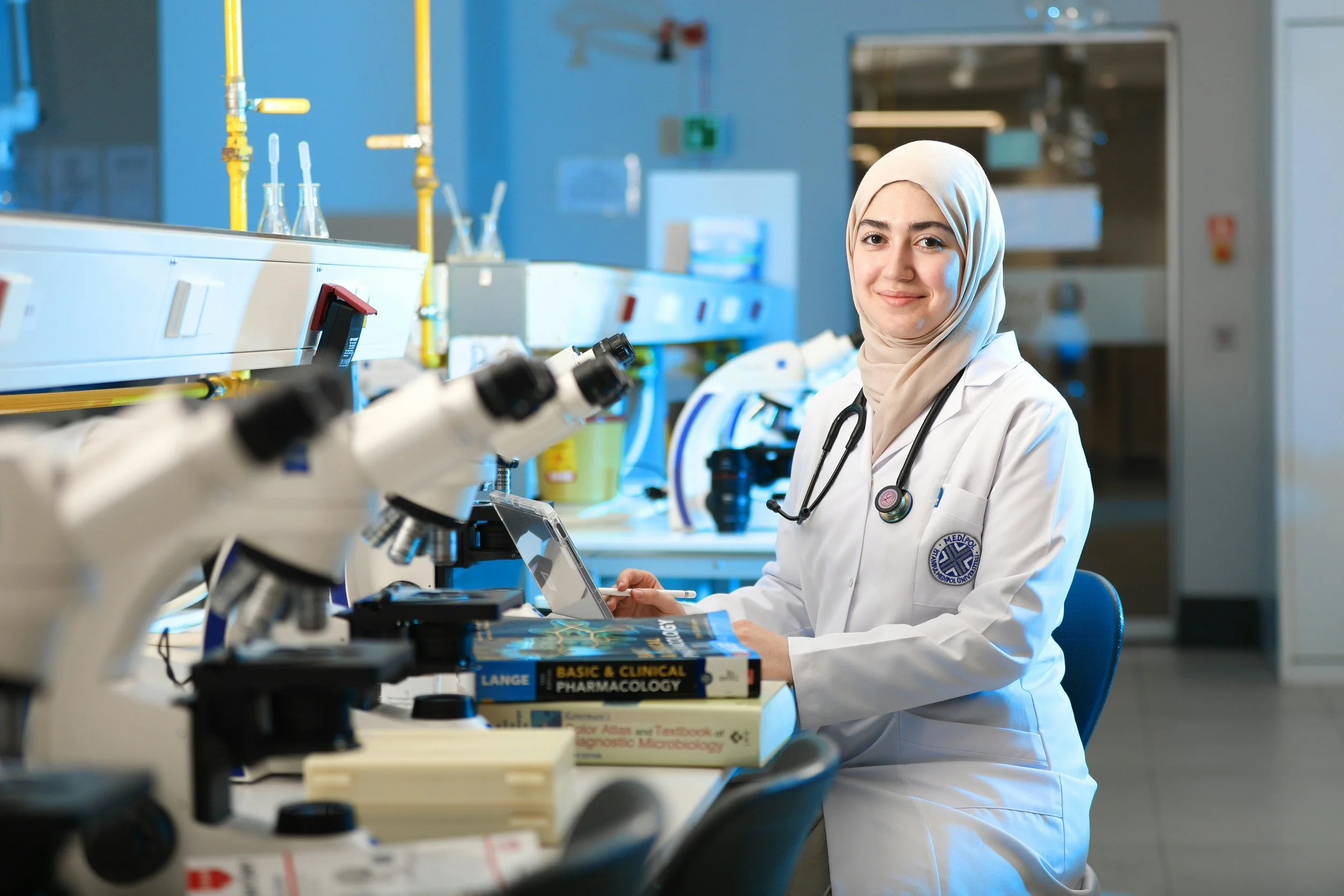 Woman sitting in a lab wearing a white coat