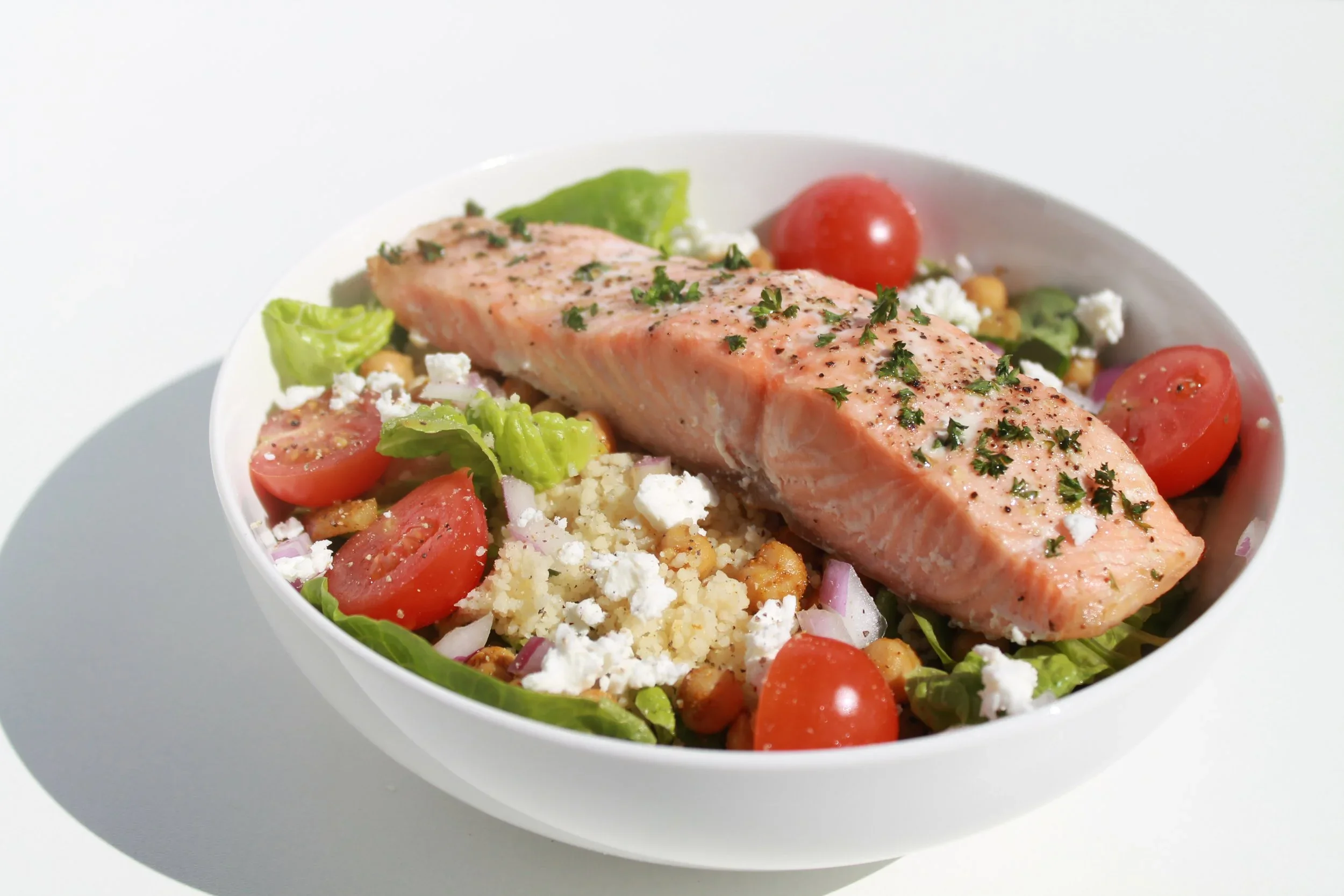 Salmon salad with cherry tomatoes, lettuce, feta cheese, and red onions.