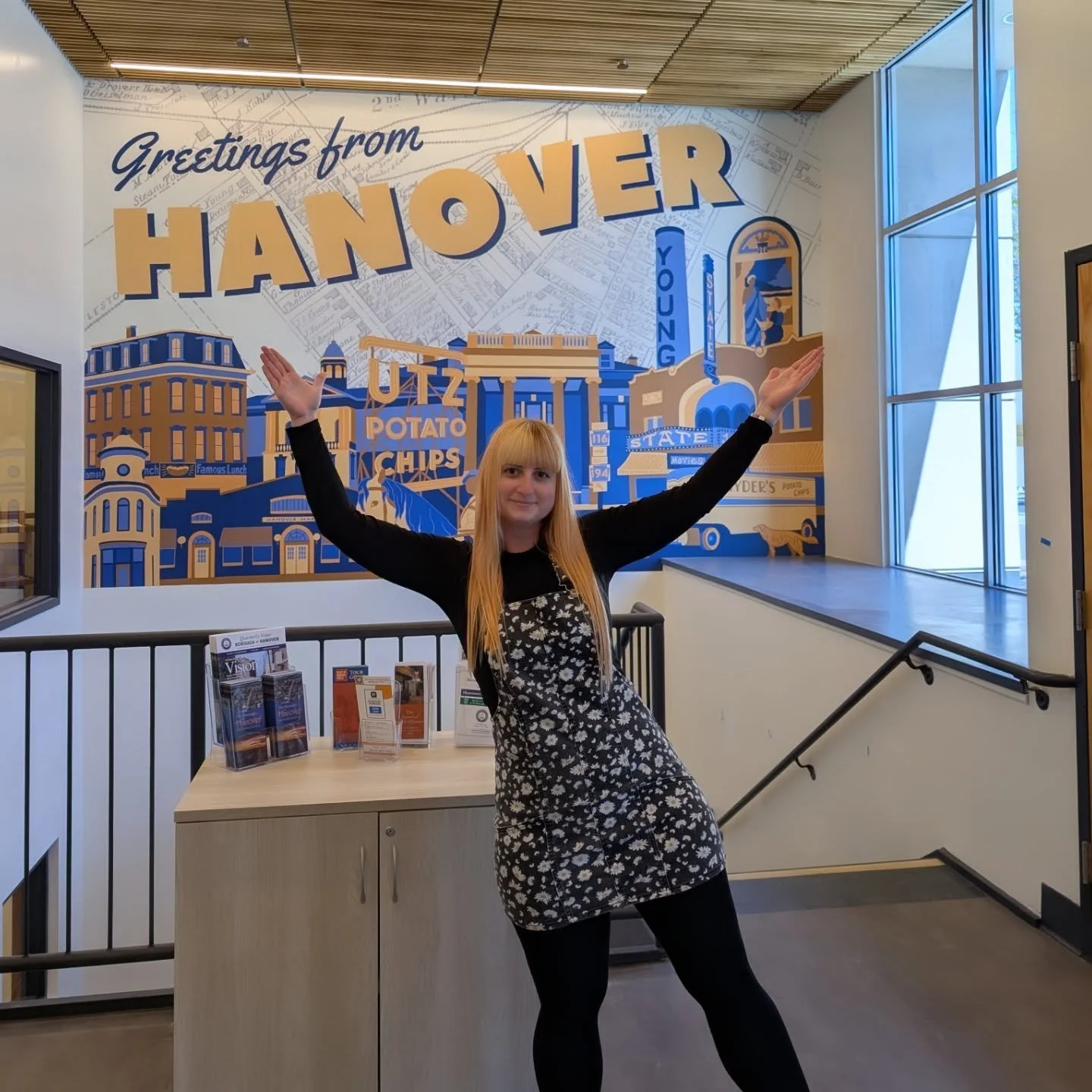 Moriah Tyler standing in front of Hanover Borough Mural located inside Hanover Borough Municipal Building.