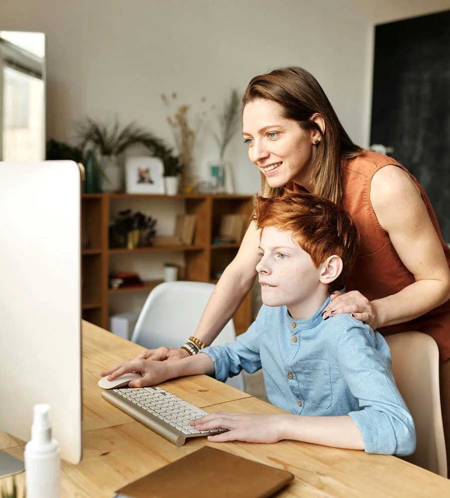 Mother and son at a desk, streaming news on computer screen
