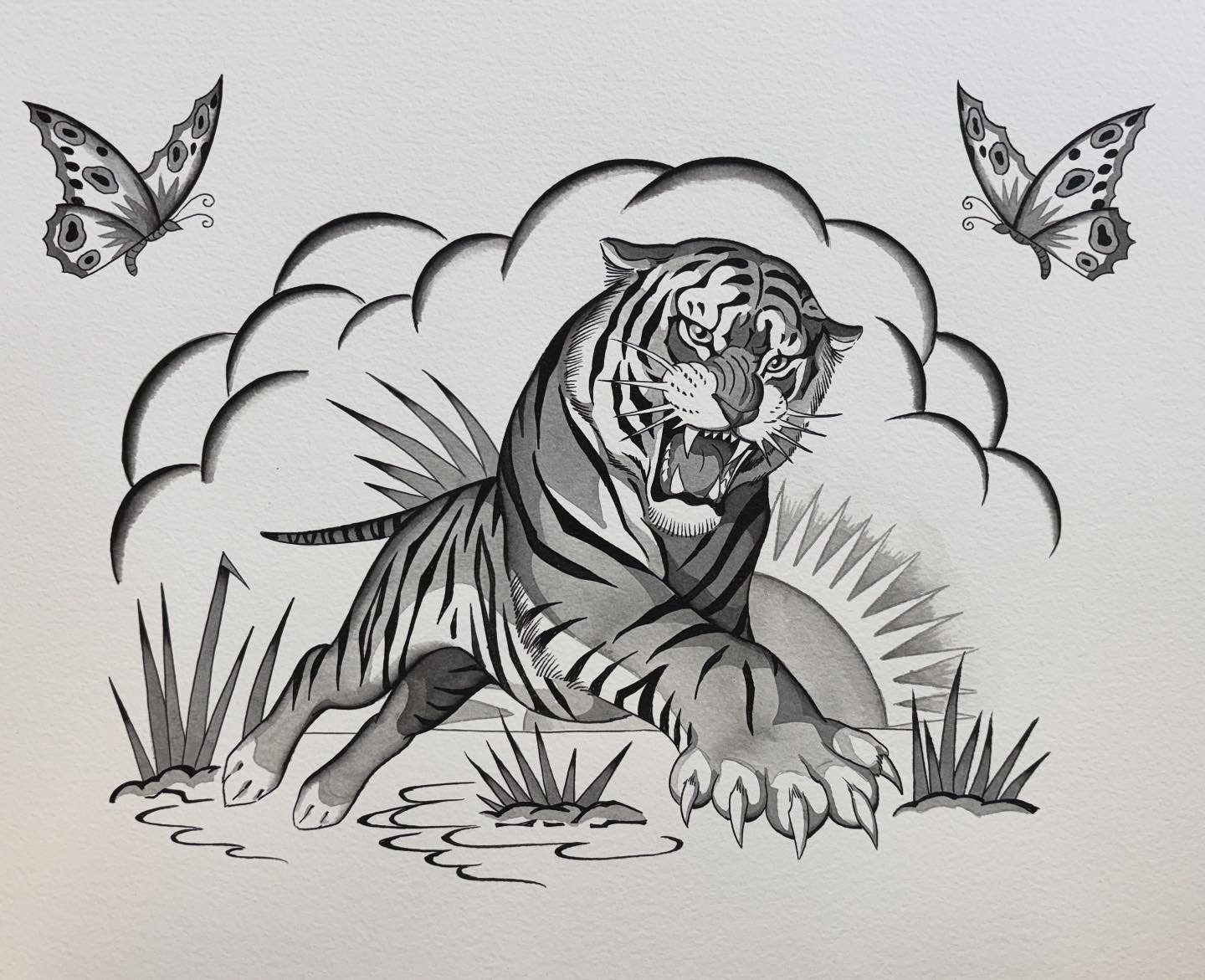 A black and white tattoo of a roaring tiger on the skin, with two butterflies flying above, surrounded by clouds and grass.