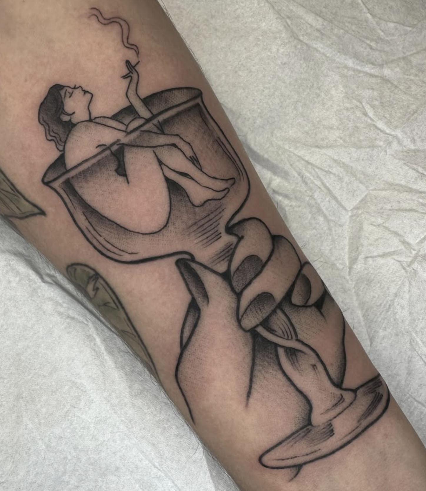 Tattoo of a woman sitting in a glass of wine, holding a cigarette.