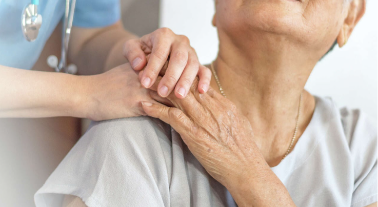 Healthcare worker assisting an elderly person with shoulder pain or discomfort.