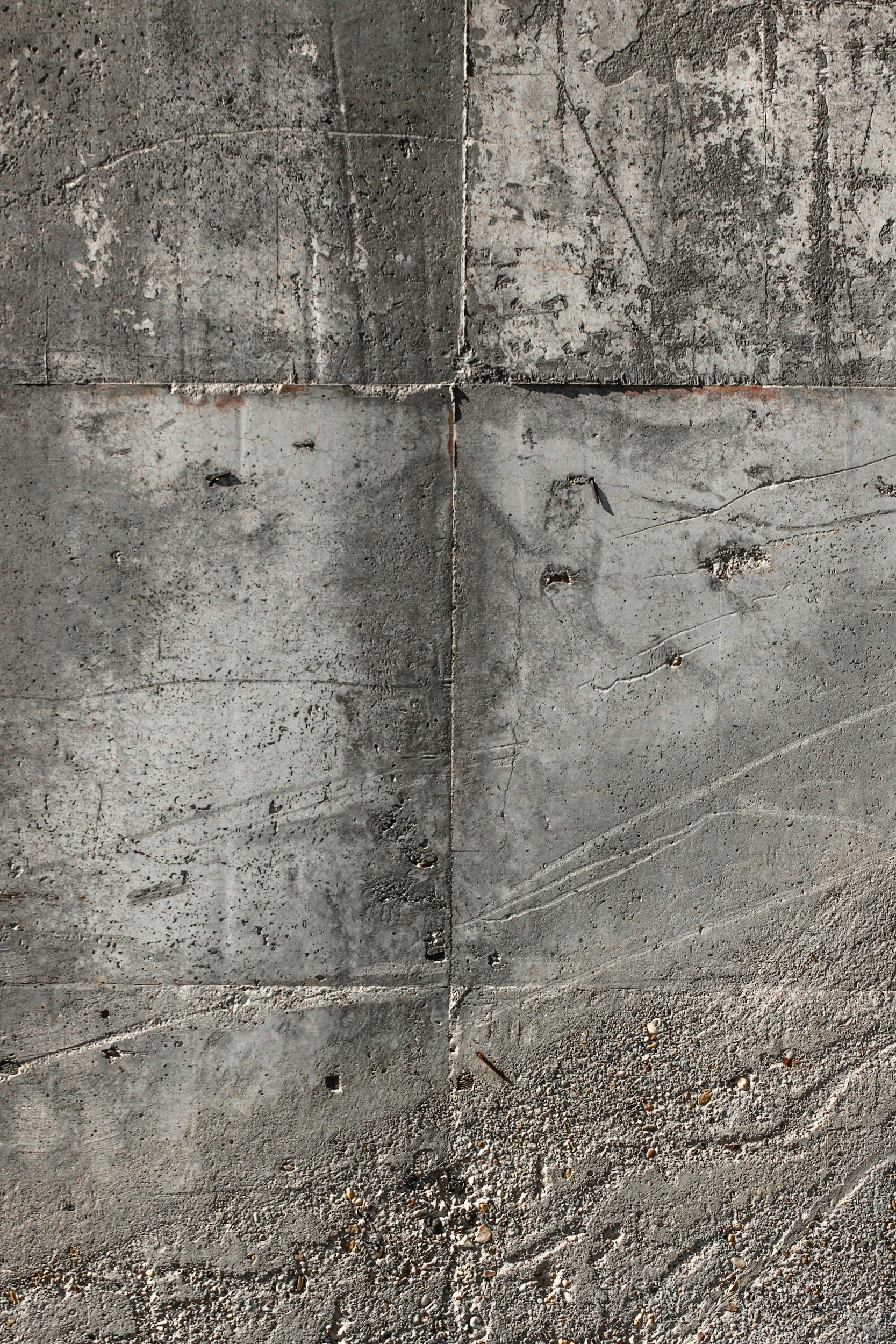 Close-up of weathered, cracked concrete slabs and gravel on the ground.