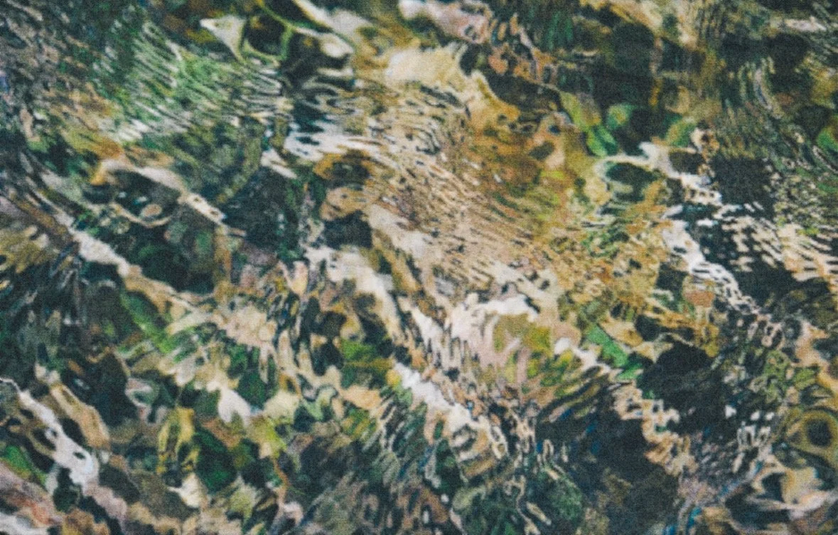 Close-up of water ripples over a multicolored, textured surface.