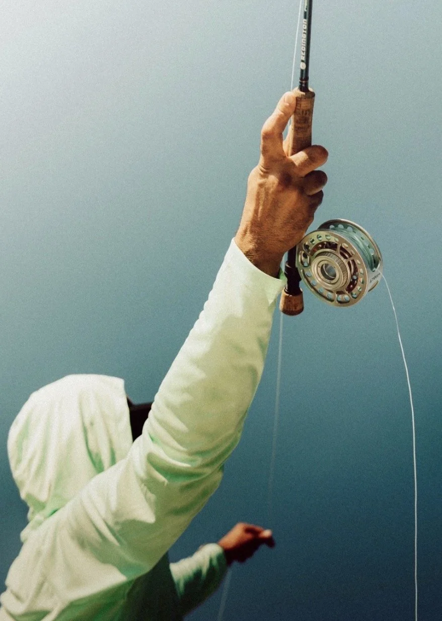 Close-up of a person holding a fishing rod against a blue sky or water background.