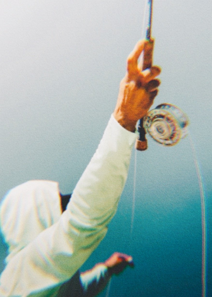 Close-up of a person's hand holding a fishing reel with fishing line, against a blurred background.