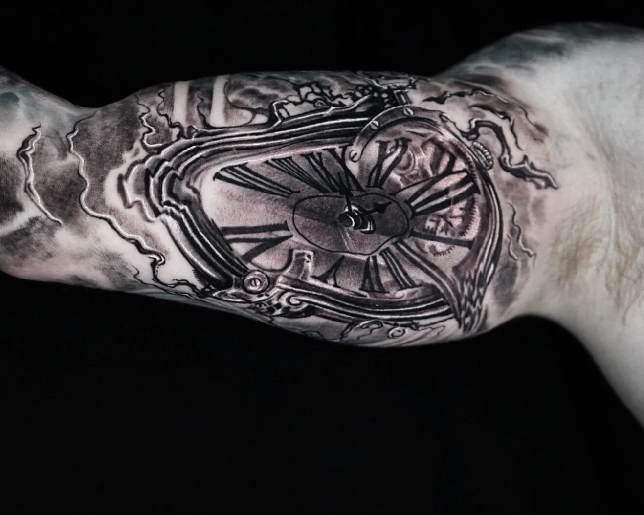 Black and gray tattoo of a pocket watch on a person's forearm, featuring Roman numerals and mechanical details.