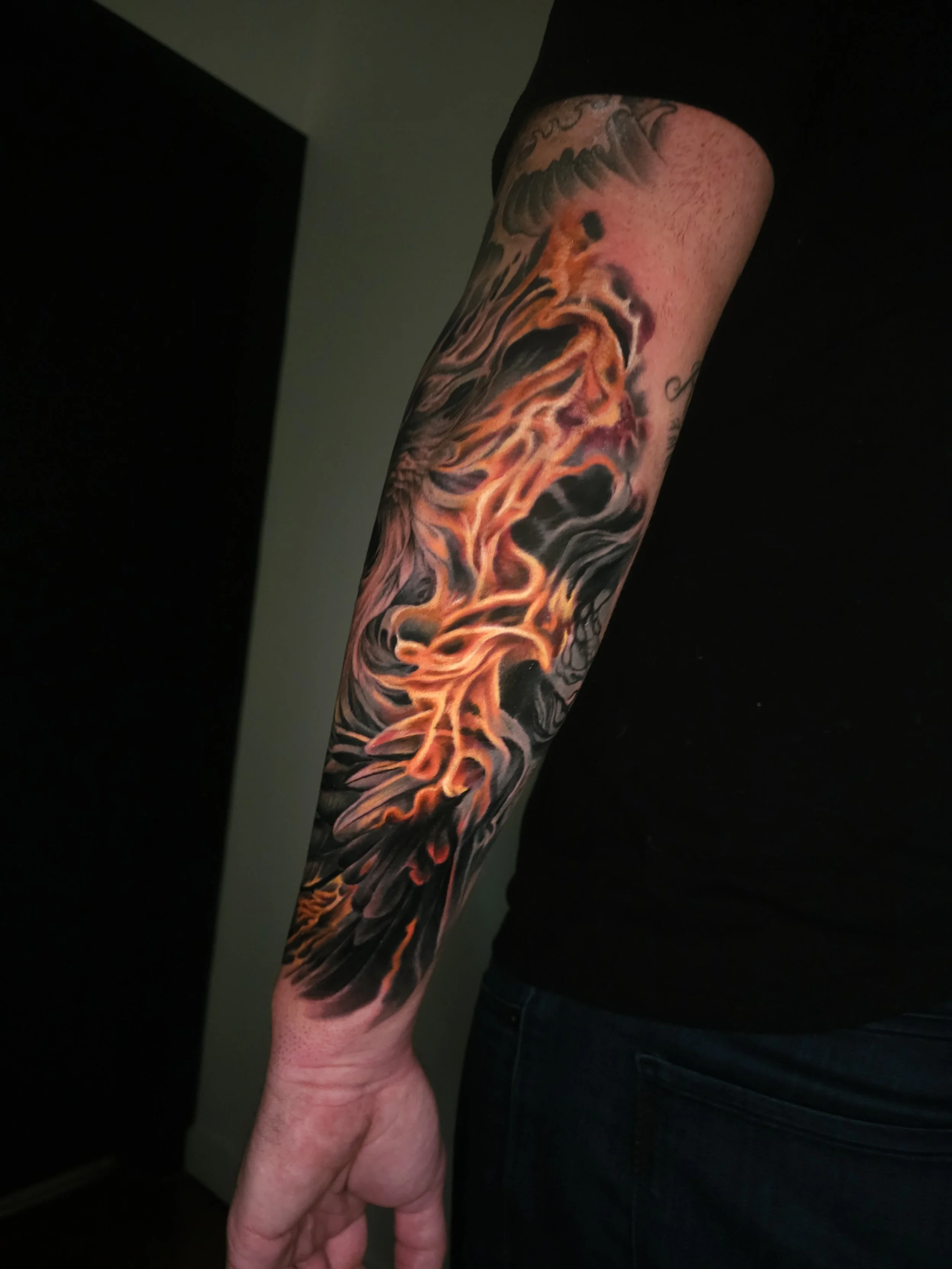 Colorful tattoo of a flaming phoenix on a person's forearm.