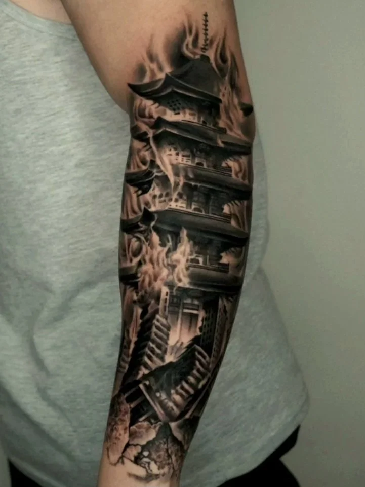 Black and gray tattoo sleeve featuring traditional Asian pagodas, smoke, and cityscape elements on a person's arm.