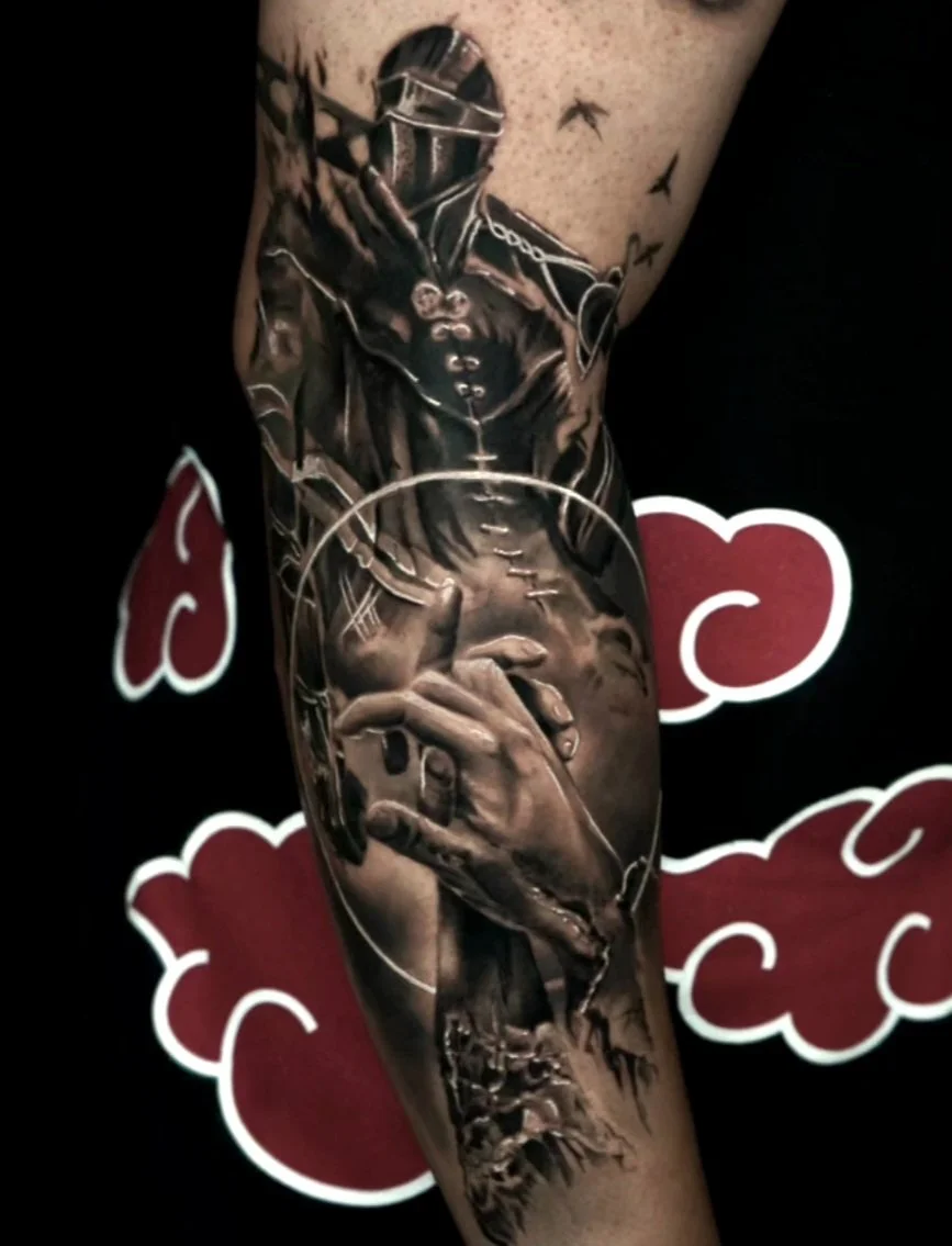 Black and gray tattoo of a person wearing a hood, holding a spray paint can, with birds flying nearby, on a person's arm.