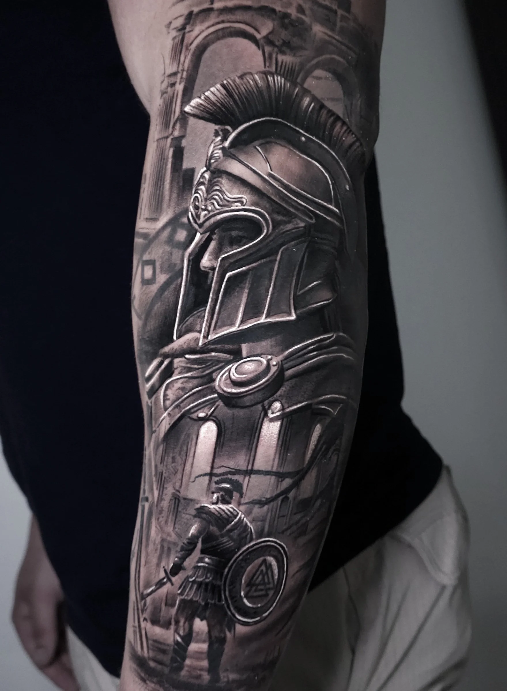 Black and gray tattoo depicting a Roman soldier and a warrior with a shield in a historical setting.