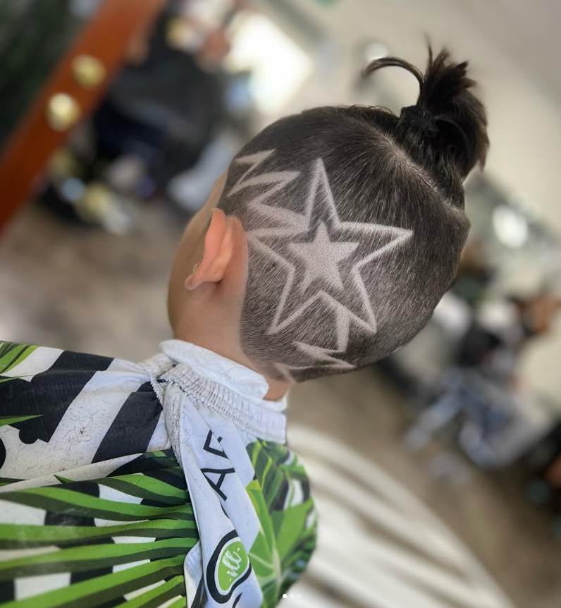 Person with a haircut featuring star and zigzag patterns shaved into the sides and back of their head.