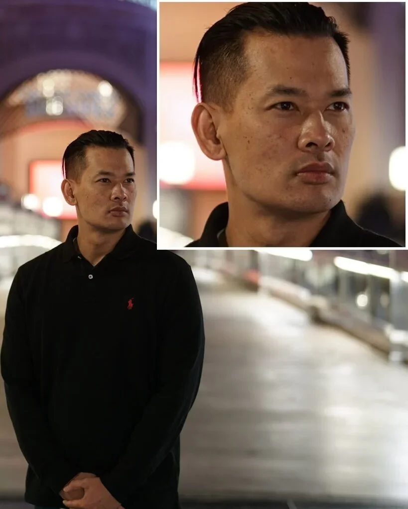 A man with short black hair and a serious expression standing in an indoor space with blurred background, wearing a black collared shirt with red logo, featured in two close-up shots and a wider shot.