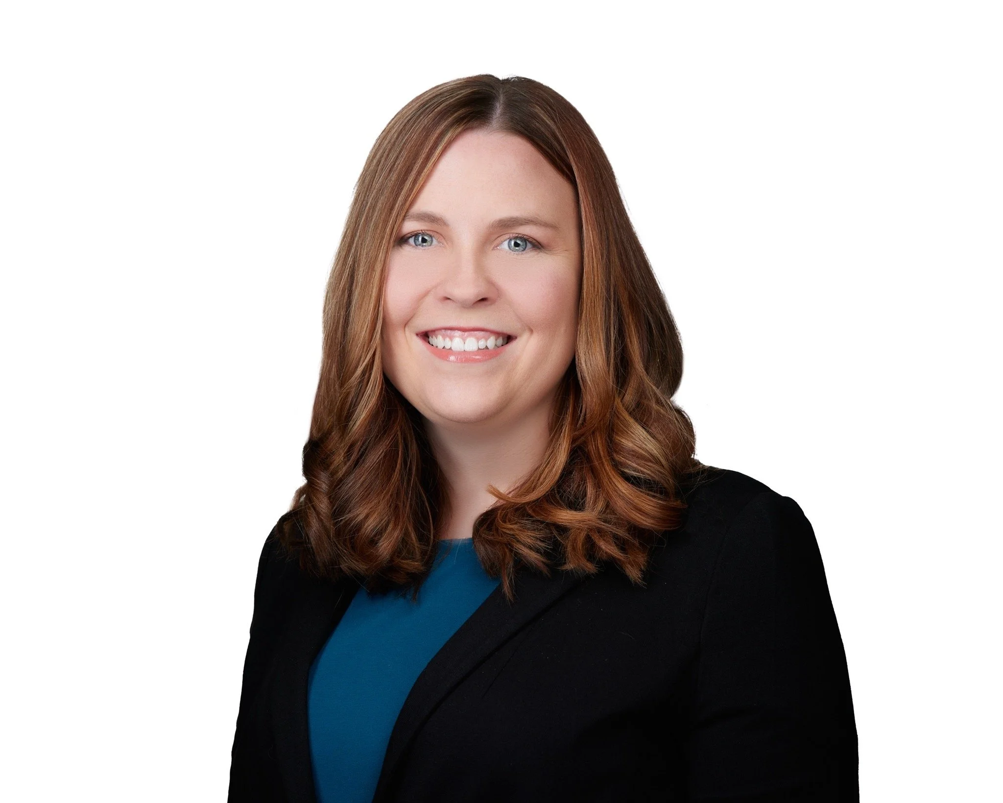 Professional headshot of a woman with shoulder-length brown hair, blue eyes, smiling, wearing a black blazer and teal top against a white background.