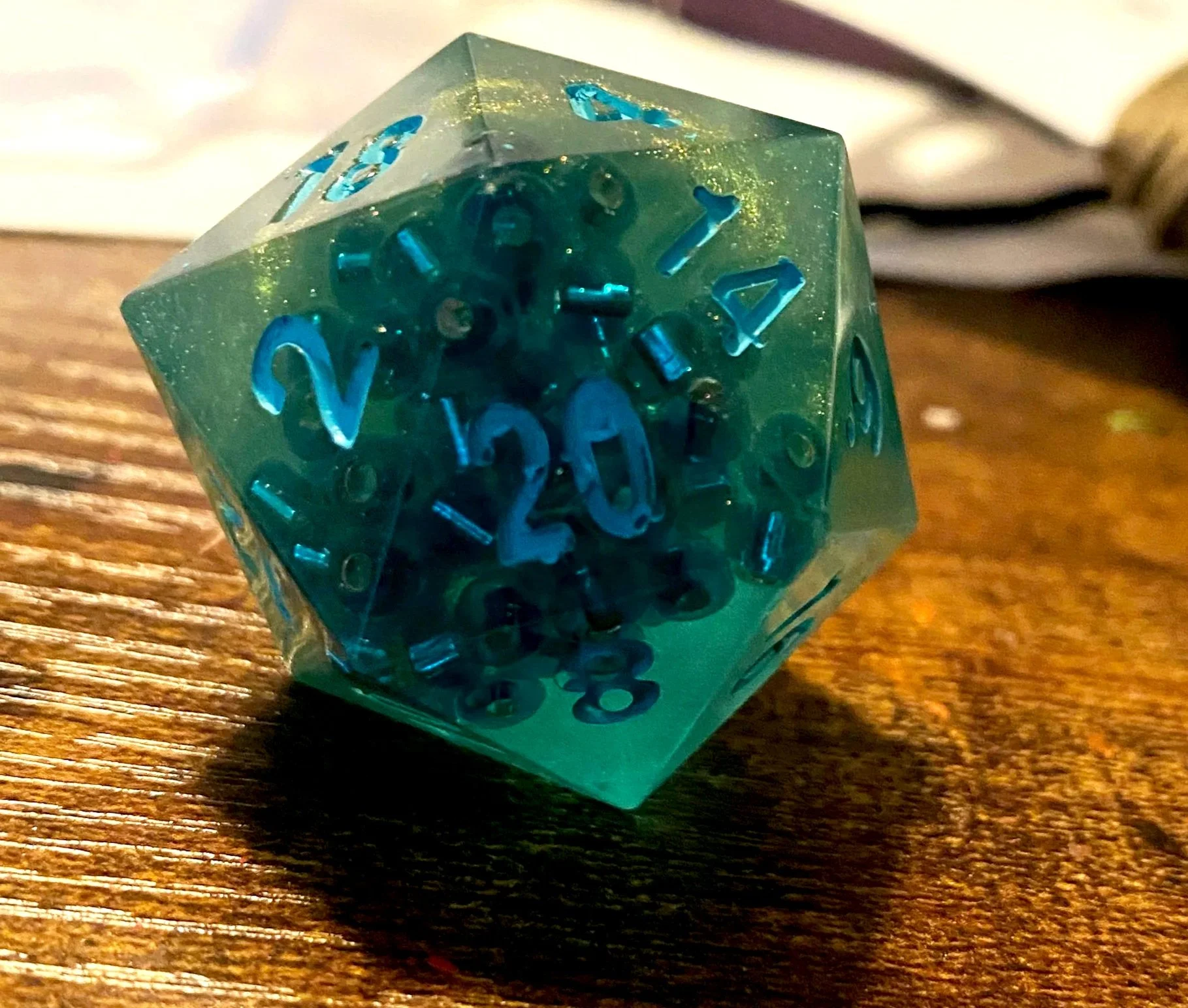 At the end of our first big campaign, I made a set of dice for each of the players that contained a die that referenced all of our characters. This was for a character with water and sea based themes. The resin was tinted to a seafoam green and featu