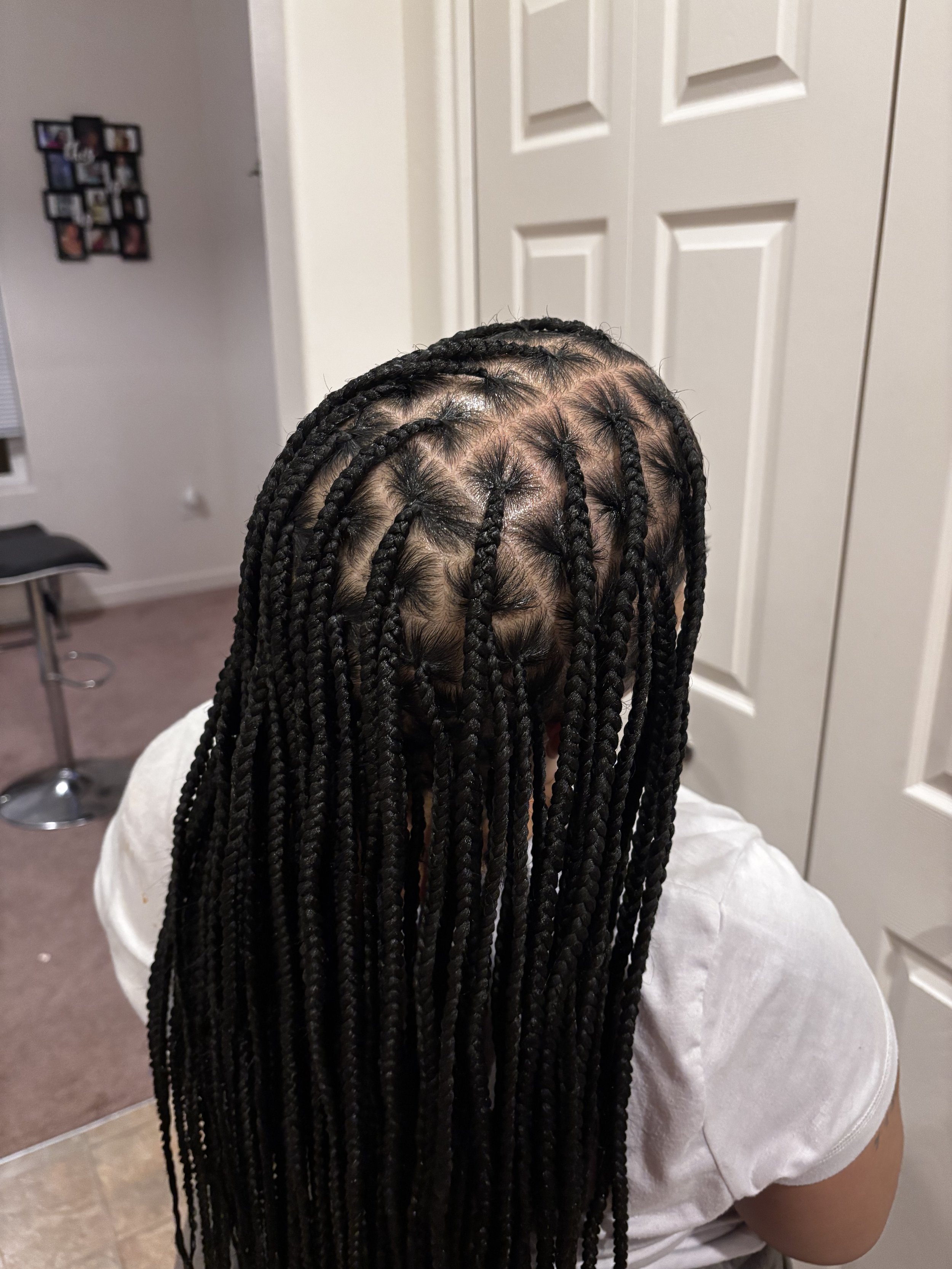 Person with long black braids in a room with white walls and closed white doors, seen from above.