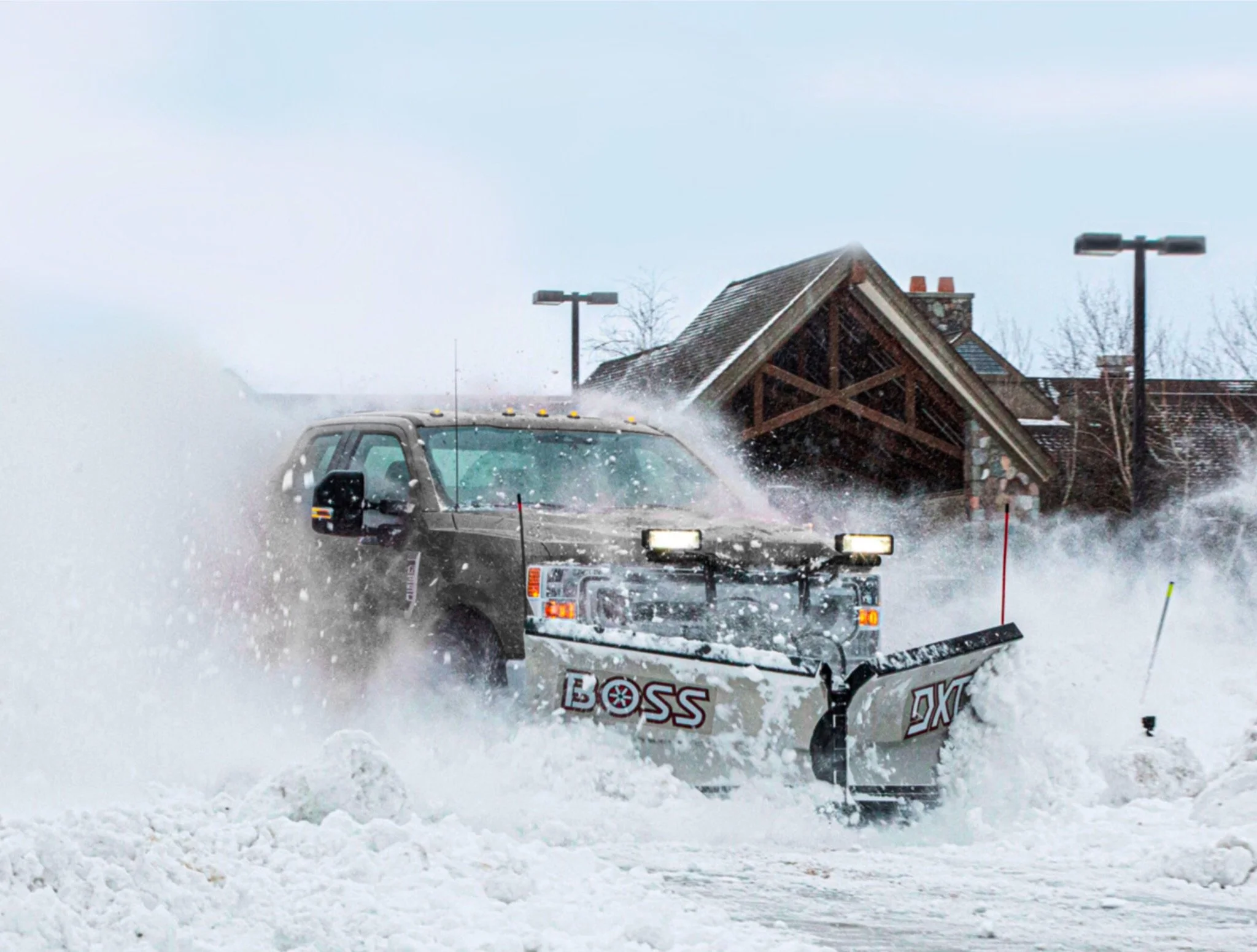 A snowplow vehicle clearing snow in front of a building during a snowstorm.